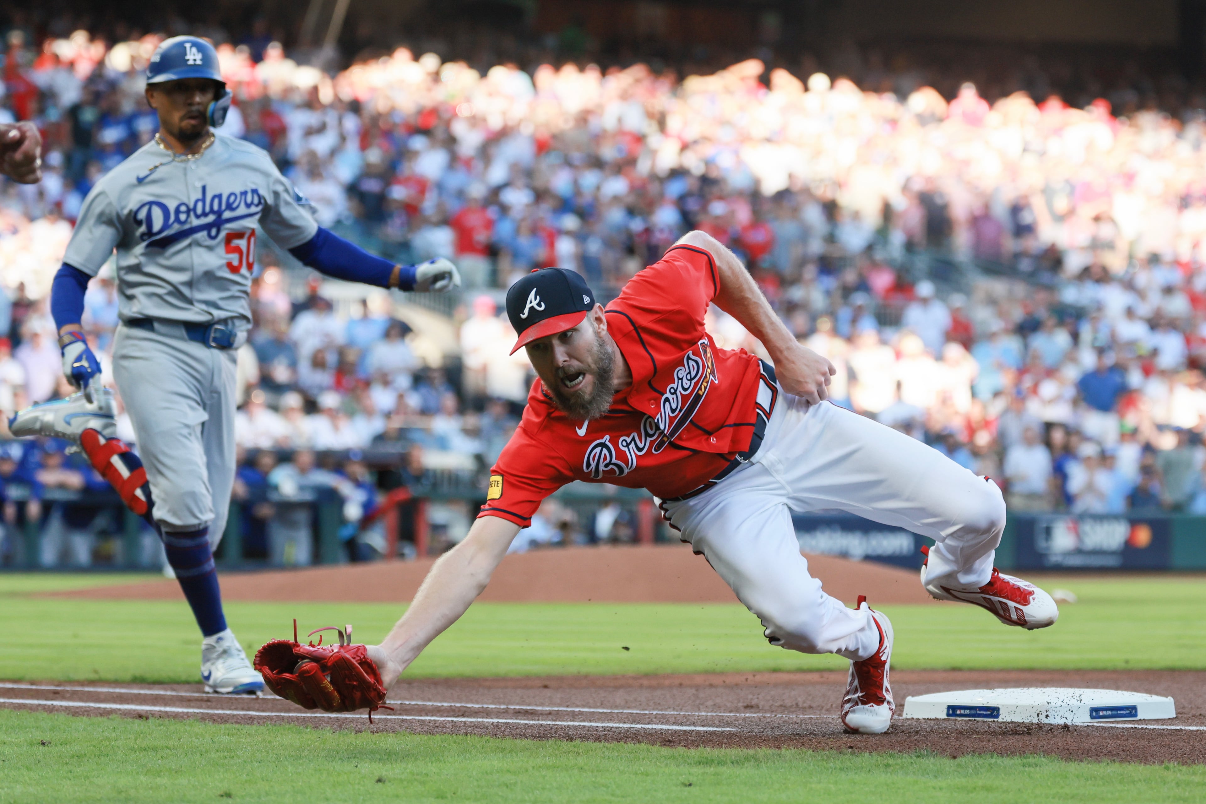 Atlanta Braves pitcher Chris Sale, right, is drawn off the bag on an awkward throw from first baseman Matt Olson on an infield hit by Los Angeles Dodgers shortstop Mookie Betts (50) during the first inning of Game 3 of the MLB National League Division Series between the Atlanta Braves and the Los Angeles Dodgers, Tuesday, Oct. 6, 2026, in Atlanta. (Jason Getz/AJC)