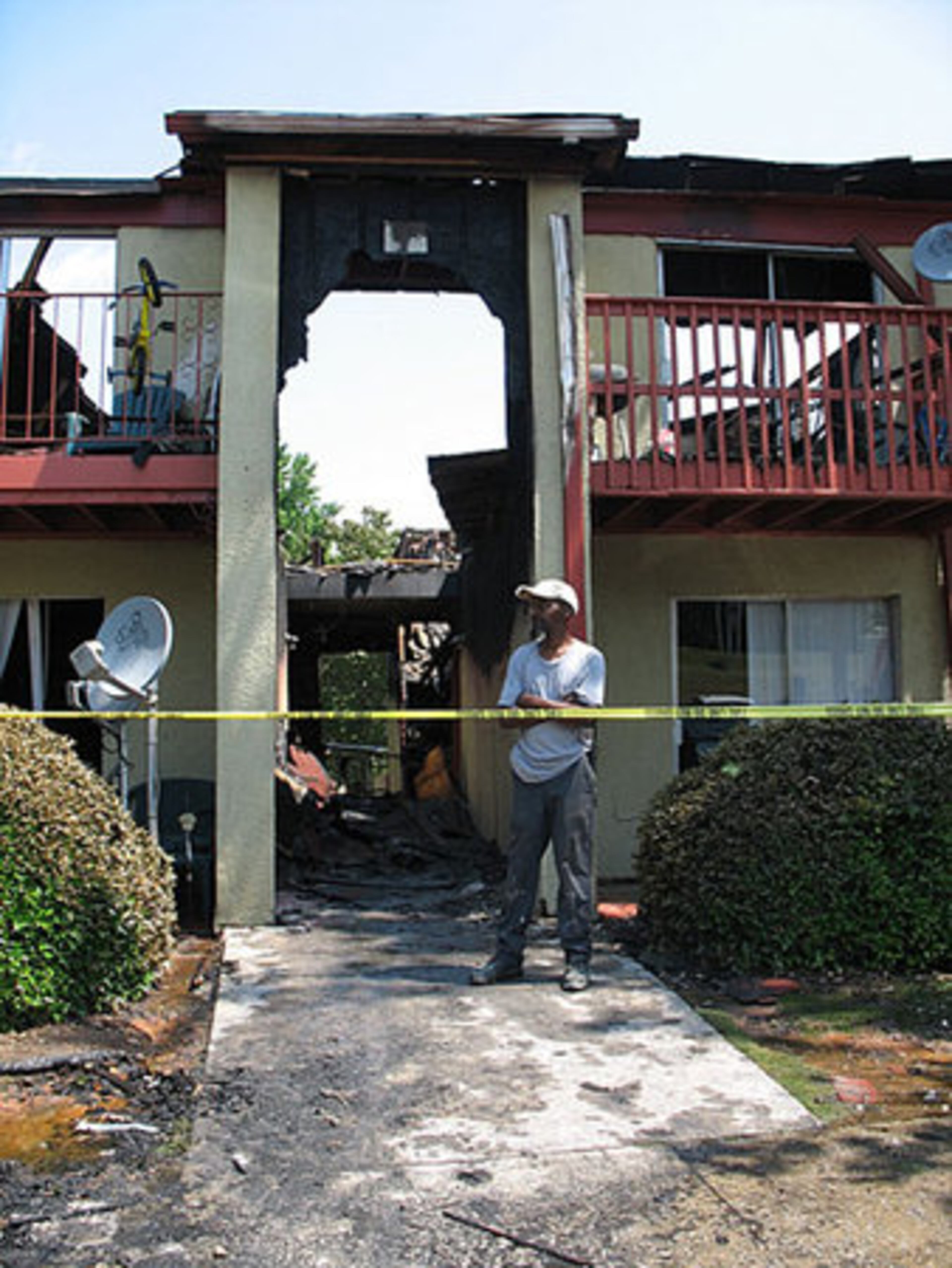 The burned-out building looms behind maintenance worker Anthony Thomas.