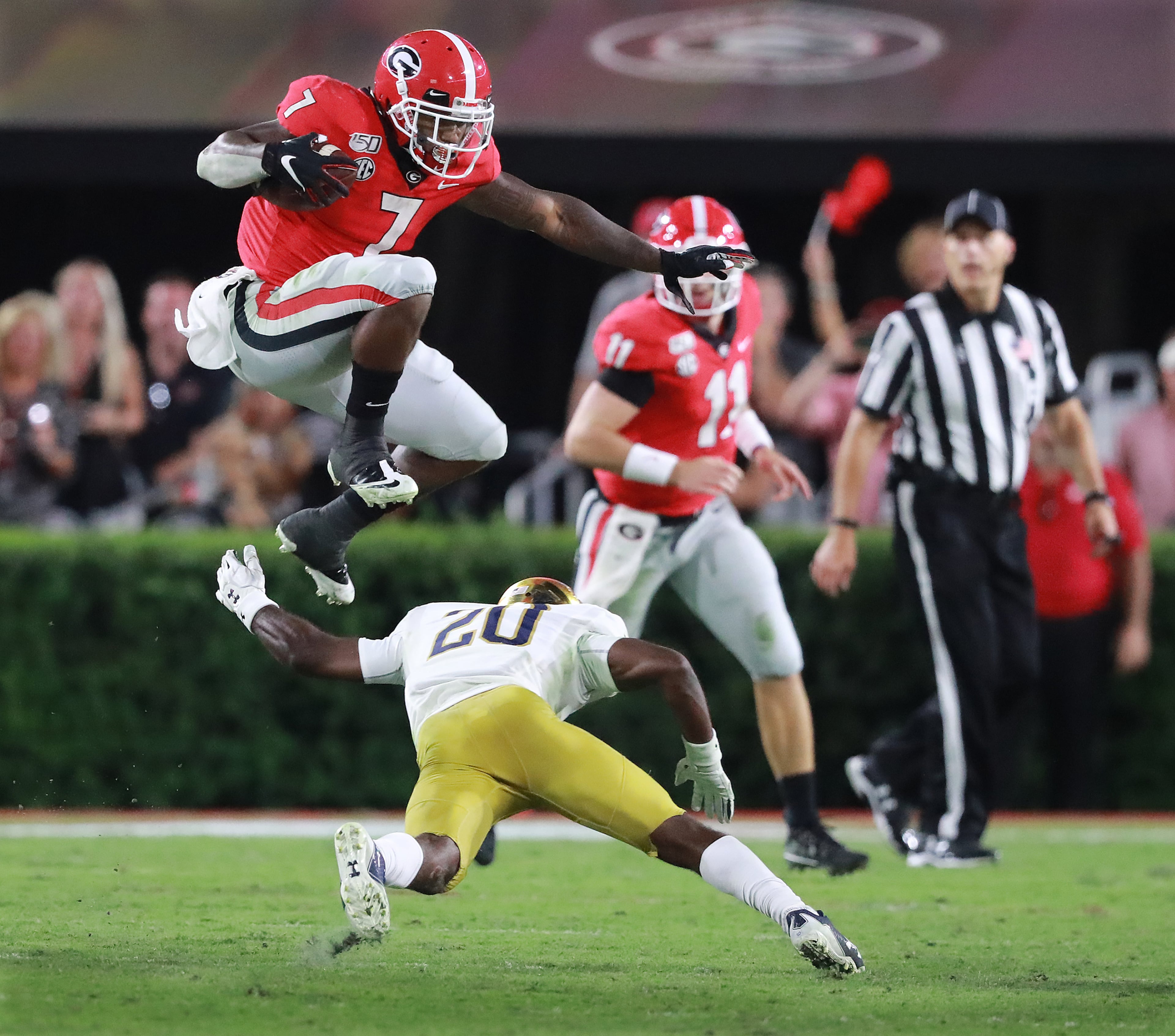 Georgia tailback D'Andre Swift leaps over Notre Dame cornerback Shaun Crawford with quarterback Jake Fromm looking on for a first down during the third quarter on the way to a 23-17 Georgia victory over Notre Dame on Saturday, Sept. 21, 2019, in Athens. Curtis Compton/ccompton@ajc.com