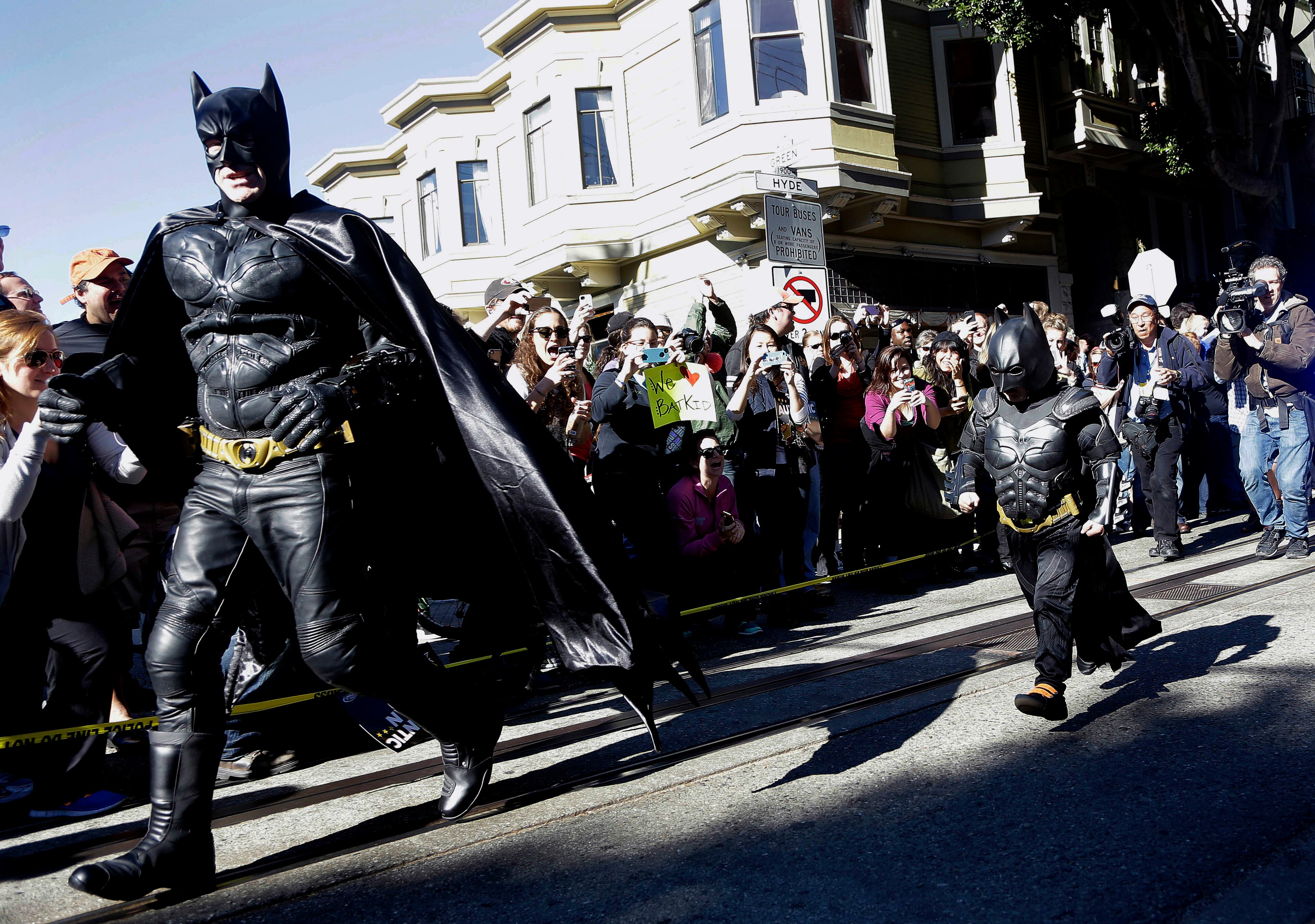Miles Scott, dressed as Batkid, right, runs with Batman after saving a damsel in distress in San Francisco, Friday, Nov. 15, 2013. San Francisco turned into Gotham City on Friday, as city officials helped fulfill Scott's wish to be "Batkid." Scott, a leukemia patient from Tulelake in far Northern California, was called into service on Friday morning by San Francisco Police Chief Greg Suhr to help fight crime, The Greater Bay Area Make-A-Wish Foundation says.
