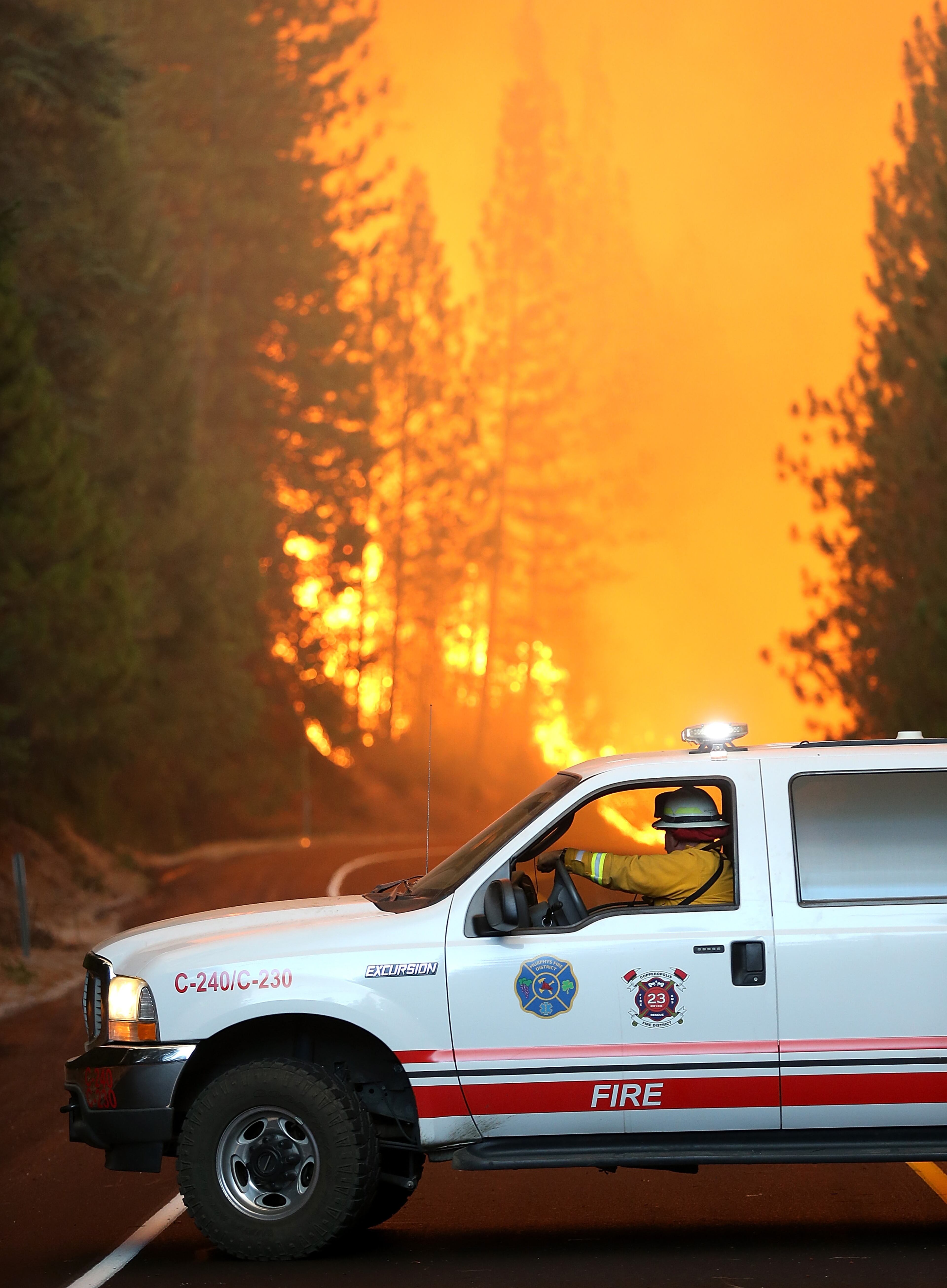GROVELAND, CA - AUGUST 24: A Murphys Fire District firefighter stops his vehicle as a massive wall of fire from the Rim Fire consumes trees along highway 120 on August 24, 2013 near Groveland, California. The Rim Fire continues to burn out of control and threatens 4,500 homes outside of Yosemite National Park. Over 2,000 firefighters are battling the blaze that has entered a section of Yosemite National Park and is currently 5 percent contained. (Photo by Justin Sullivan/Getty Images)