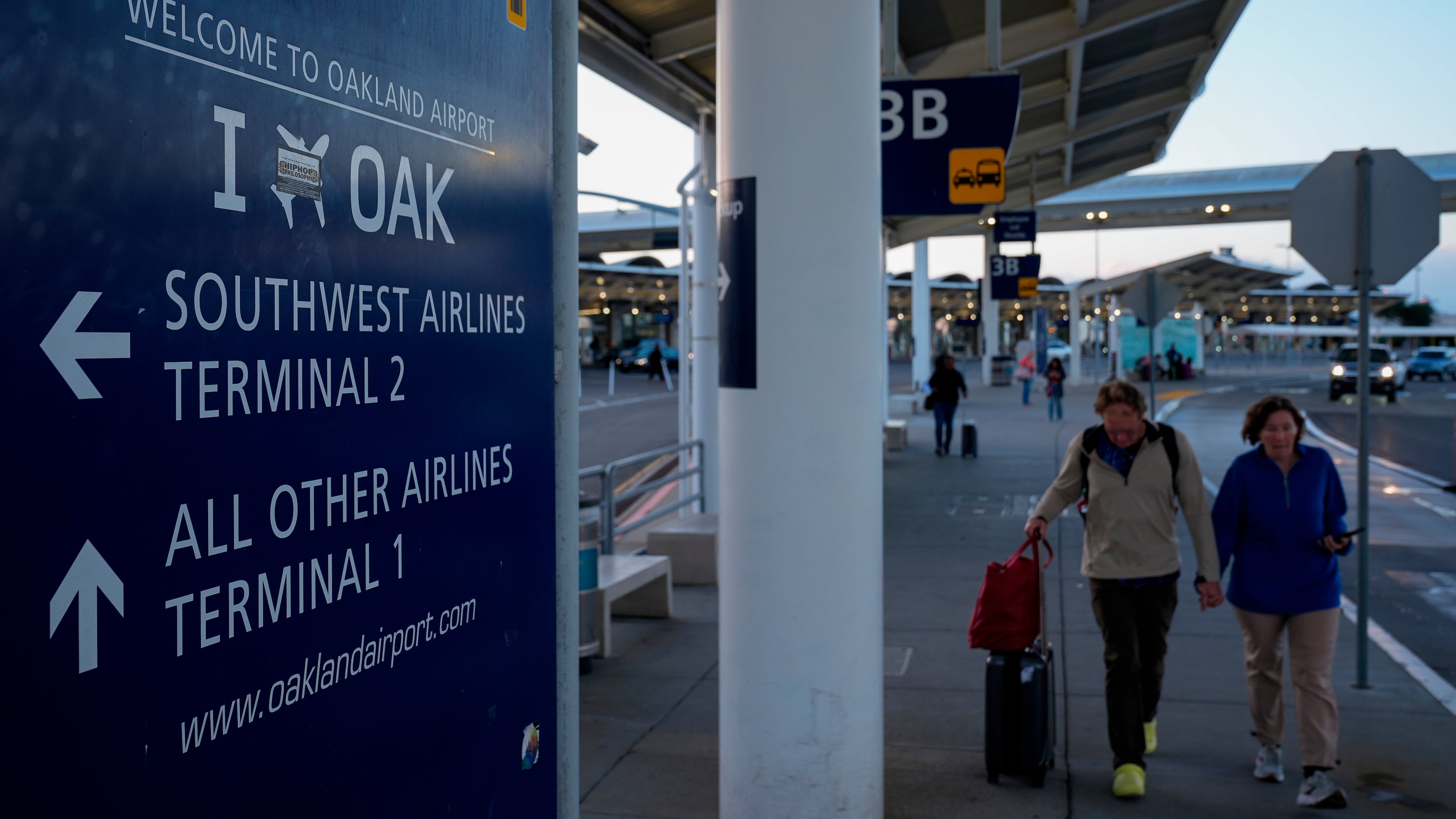 FILE - Travelers walk toward the entrance of Oakland's international airport Nov. 13, 2024, in Oakland, Calif. (AP Photo/Godofredo A. Vásquez, File)