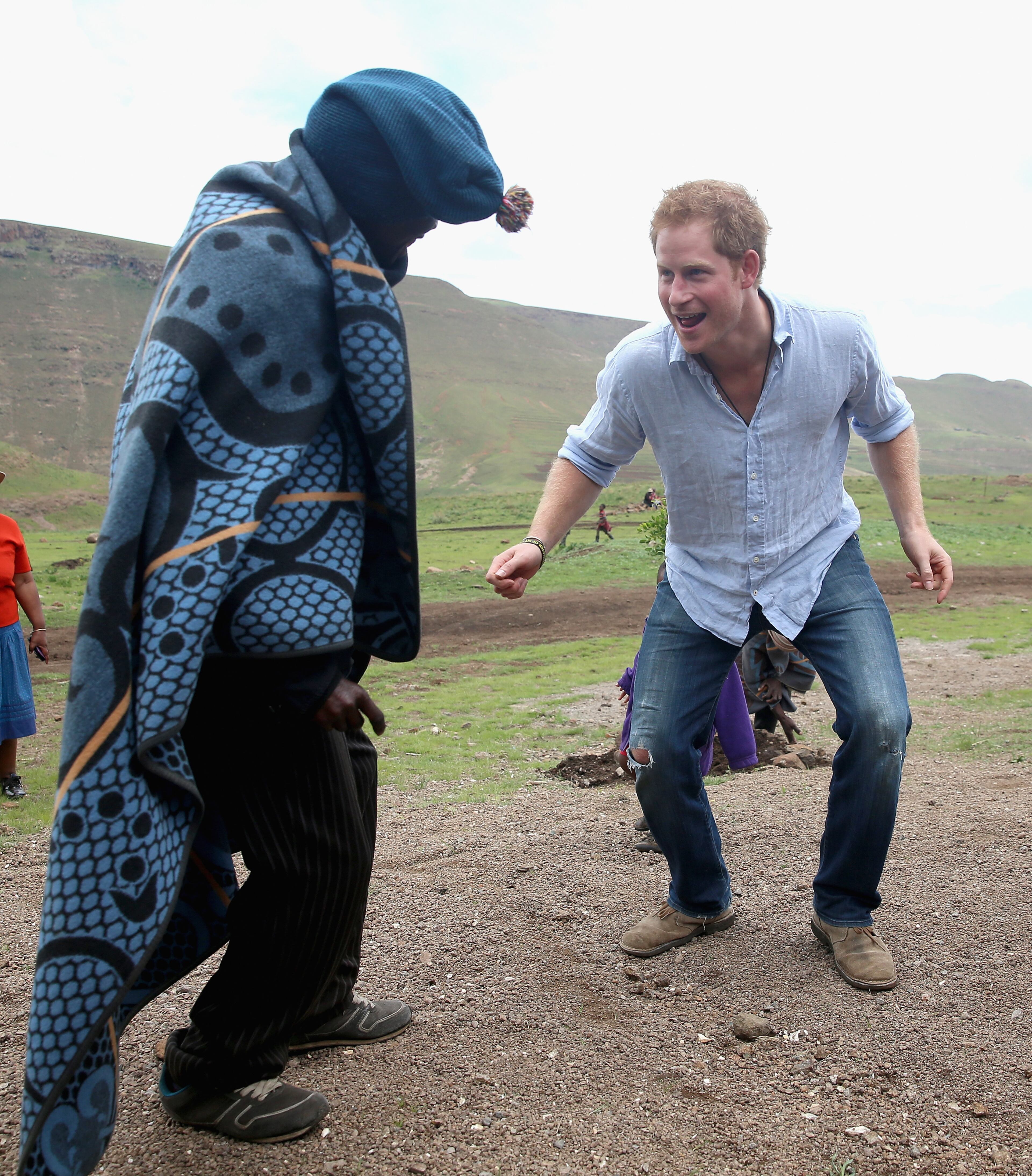 MOKHOTLONG, LESOTHO - DECEMBER 08: Prince Harry dances with the village chief during a visit to a herd boy night school constructed by Sentebale on December 8, 2014 in Maseru, Lesotho. Prince Harry was visiting Lesotho to see the work of his charity Sentebale. Sentebale provides healthcare and education to vulnerable children in Lesotho, Southern Africa. The particular theme of his visit was to check on the progress of the Mamohato Childrens Centre which will provide vital support to children affected by HIV. Prince Harry founded Sentebale (which means Forget Me Not in Sesotho) with Prince Seeiso in 2006. (Photo by Chris Jackson/Getty Images for Sentebale)