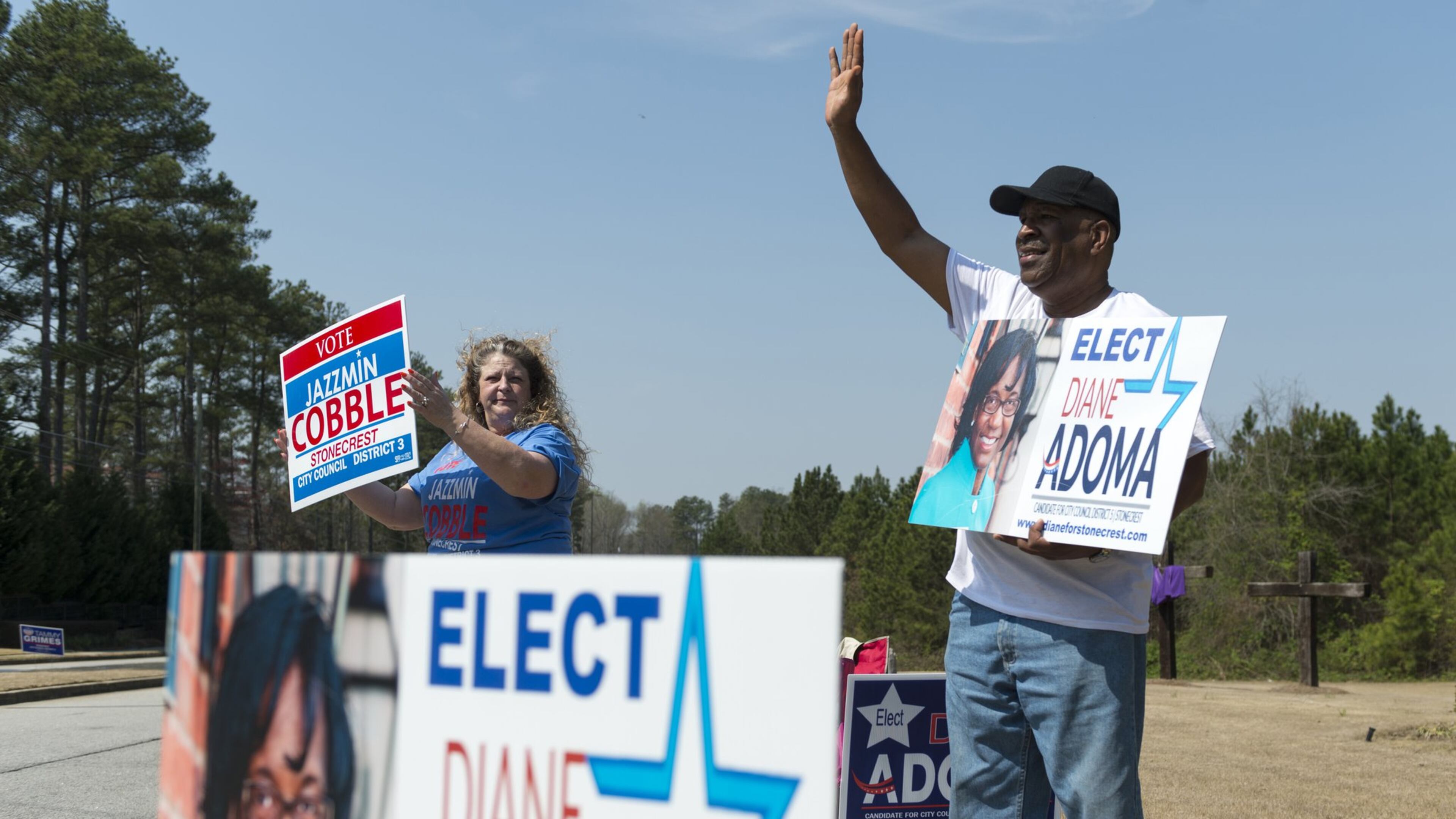 Jim Yates, right, and Shelia Messamore, left, wave to passing cars outside the polling station at New Birth Missionary Baptist Church in Atlanta in March. Candidates for local offices file campaign reports to their local jurisdiction, a process that can make it harder for citizens to access them. (DAVID BARNES / DAVID.BARNES@AJC.COM)