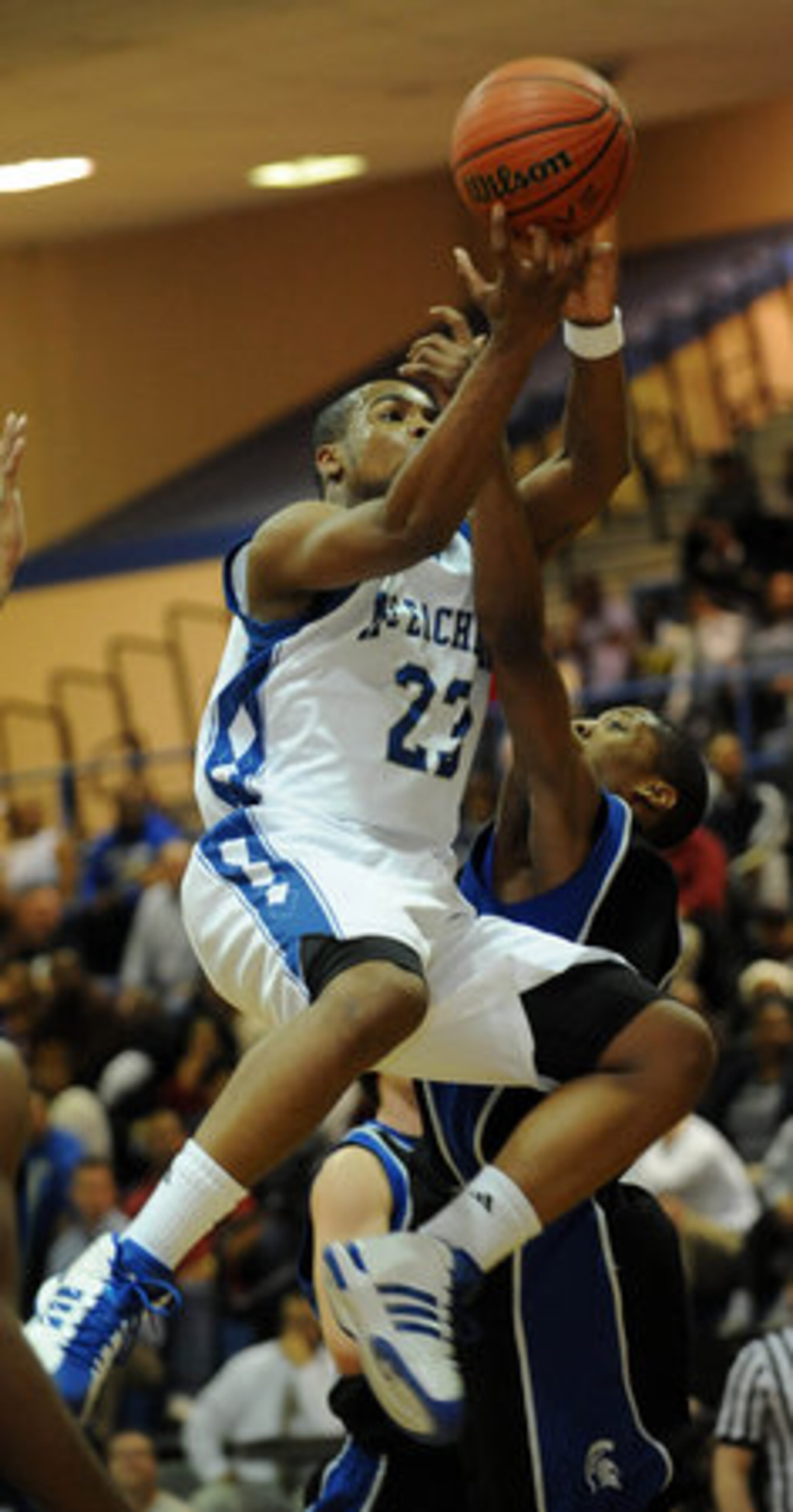 McEachern's Trae Golden (23) goes airborne over Campbell's Roderick Perkins (1) during 1st half basketball action.