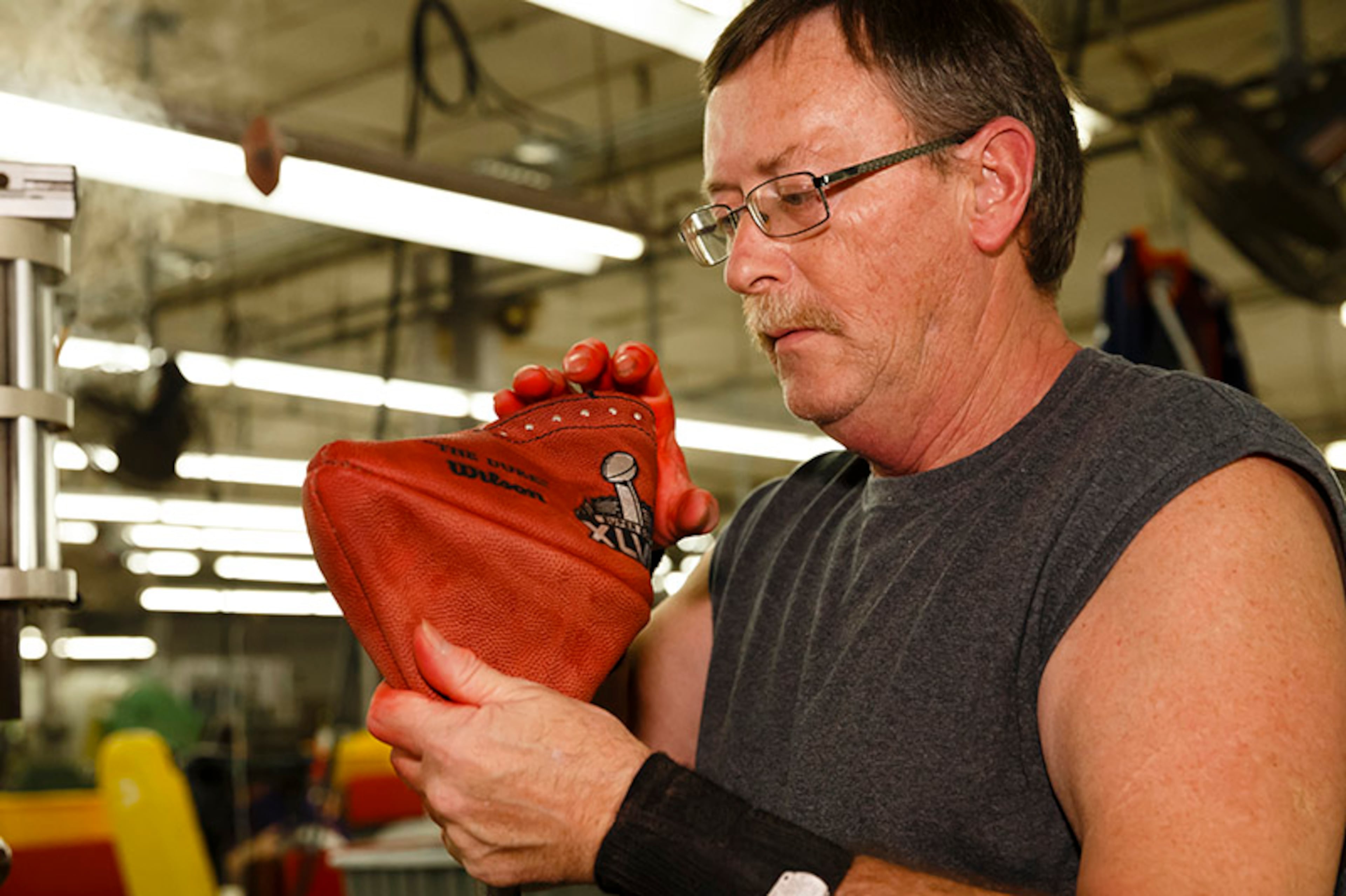 The official Super Bowl XLVIII game ball starts off as four measured curved sheets of pigskin stamped with official logos and etchings that are sewn together. Mark Connelly then turns the ball into shape.