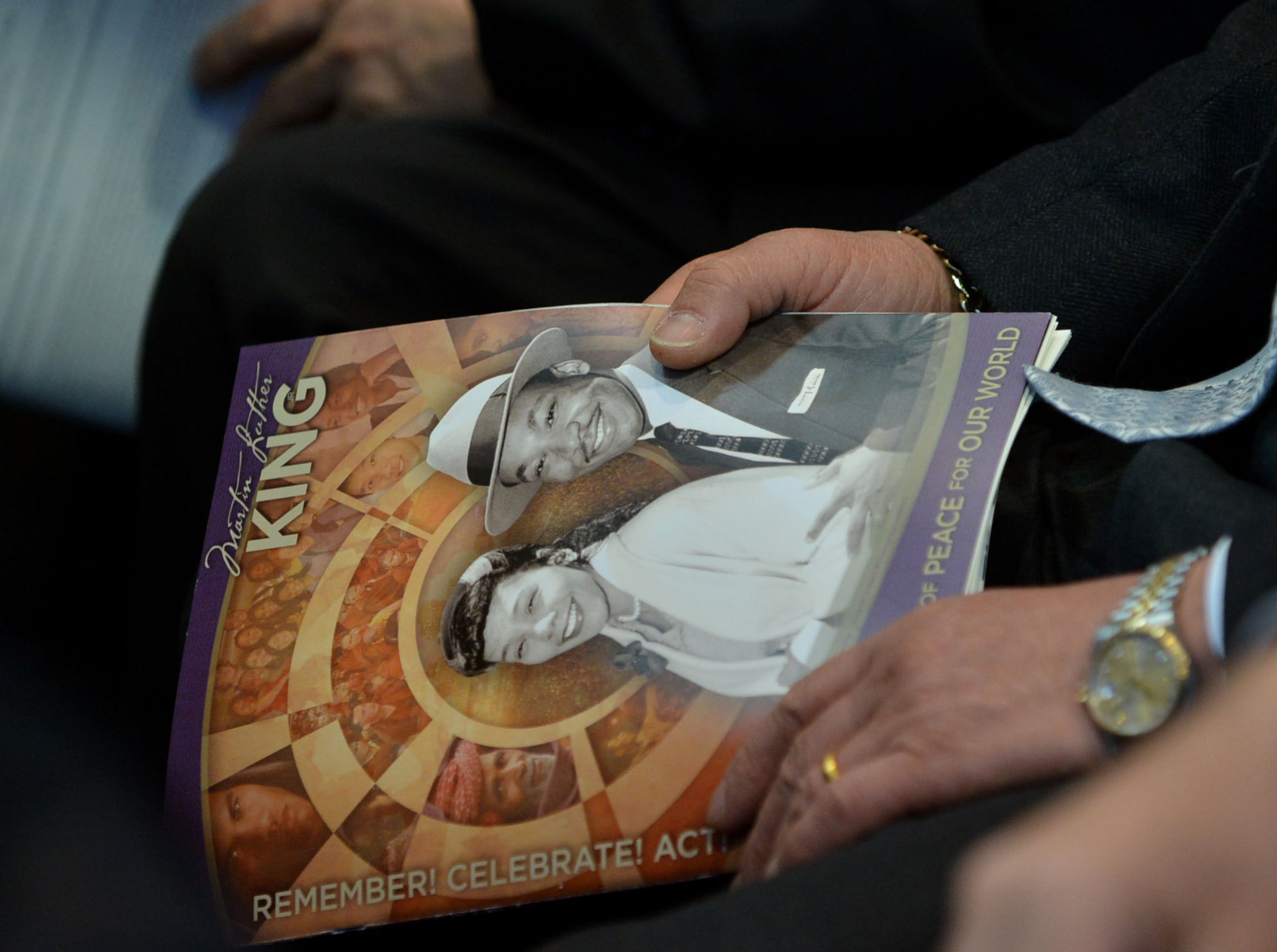 A member of the crowd holds a commemorative program.