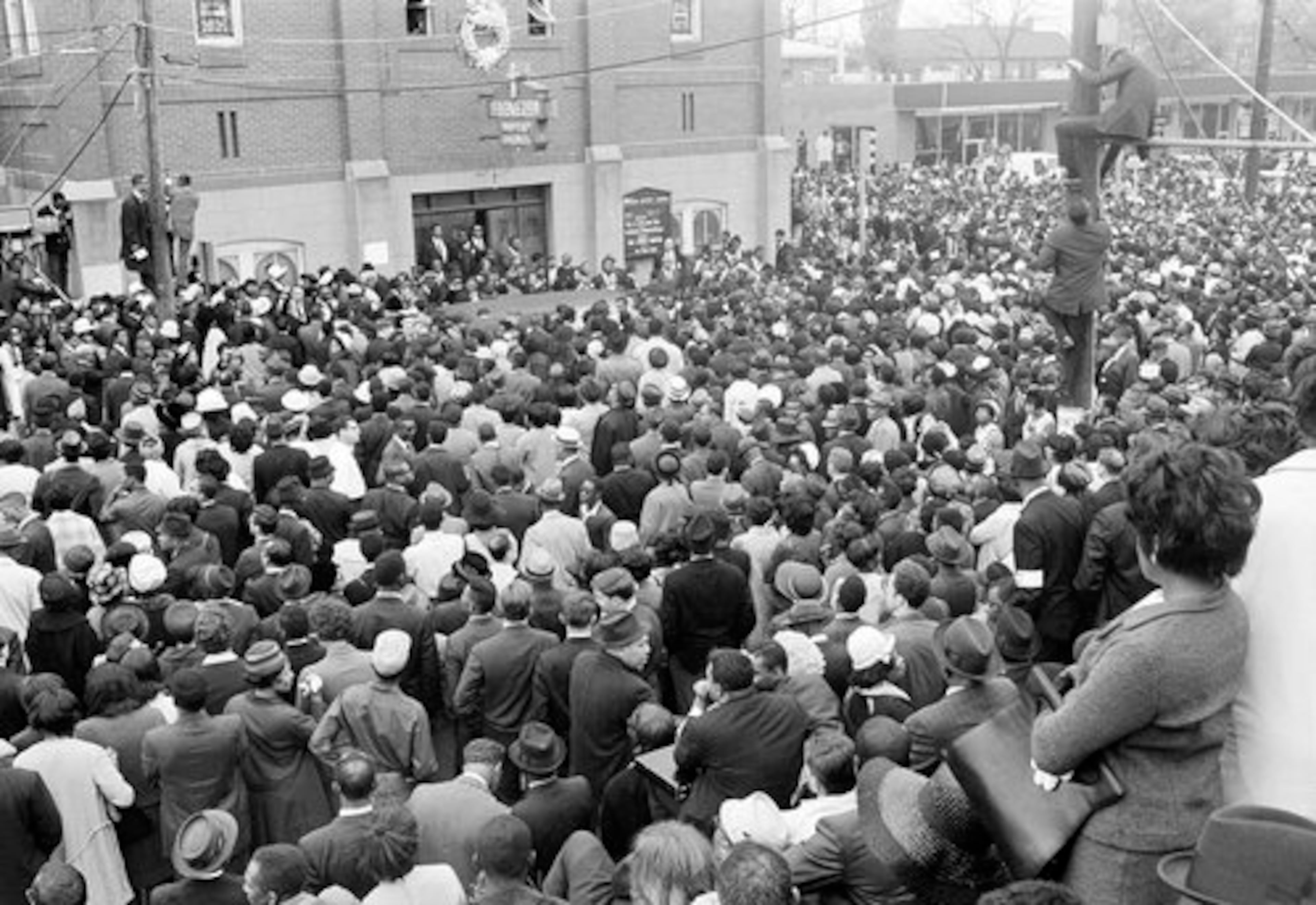 Masses of people crowd the street in front of Ebenezer Baptist Church in Atlanta, April 9, 1968, partially hiding the hearse parked in front of the door. The hearse will take the body of slain civil rights leader Dr. Martin Luther King, Jr., from the church to Morehouse College for additional funeral services.