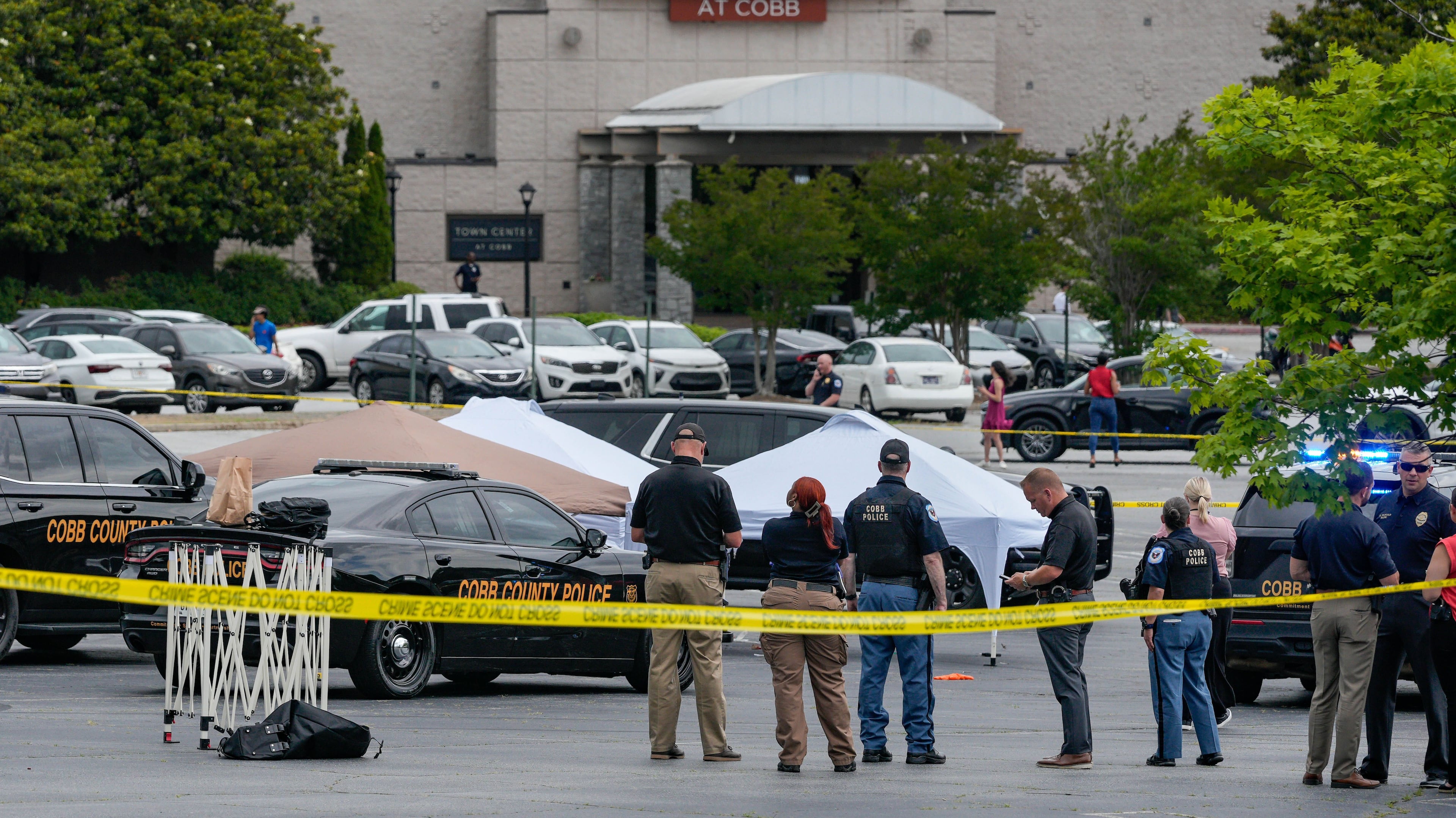 Law enforcement officials gather behind crime scene tape Wednesday afternoon at the Town Center at Cobb amid an officer-involved shooting investigation. (Ben Hendren for the AJC).