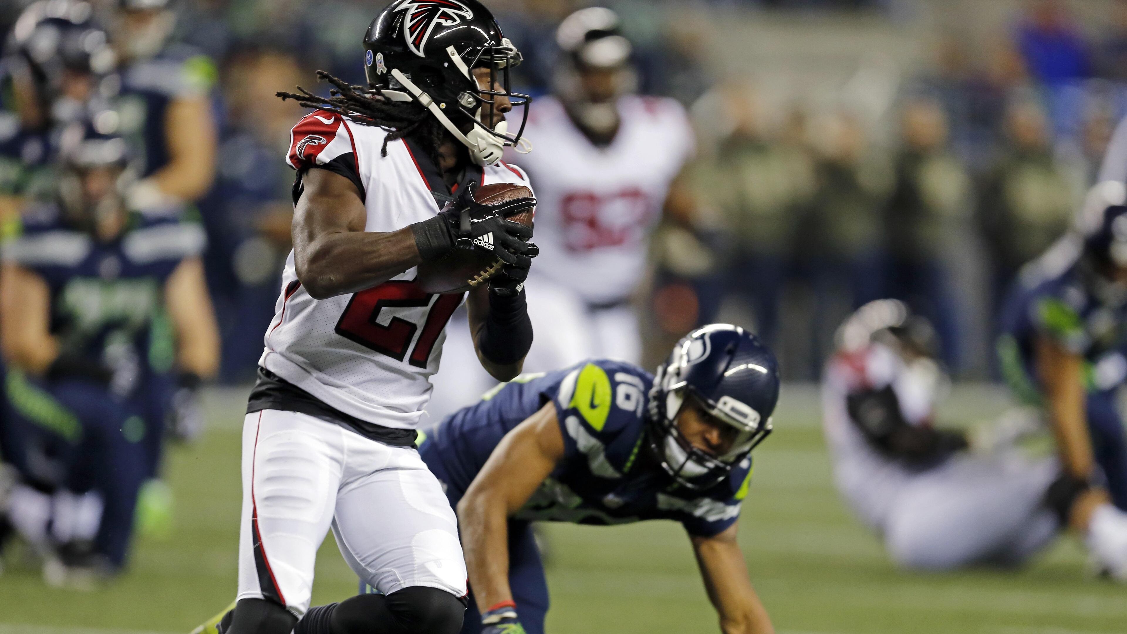 Atlanta Falcons' Desmond Trufant (21) runs with the ball after intercepting it as Seattle Seahawks' Tyler Lockett tumbles behind in the first half of an NFL football game, Monday, Nov. 20, 2017, in Seattle. (AP Photo/Stephen Brashear)