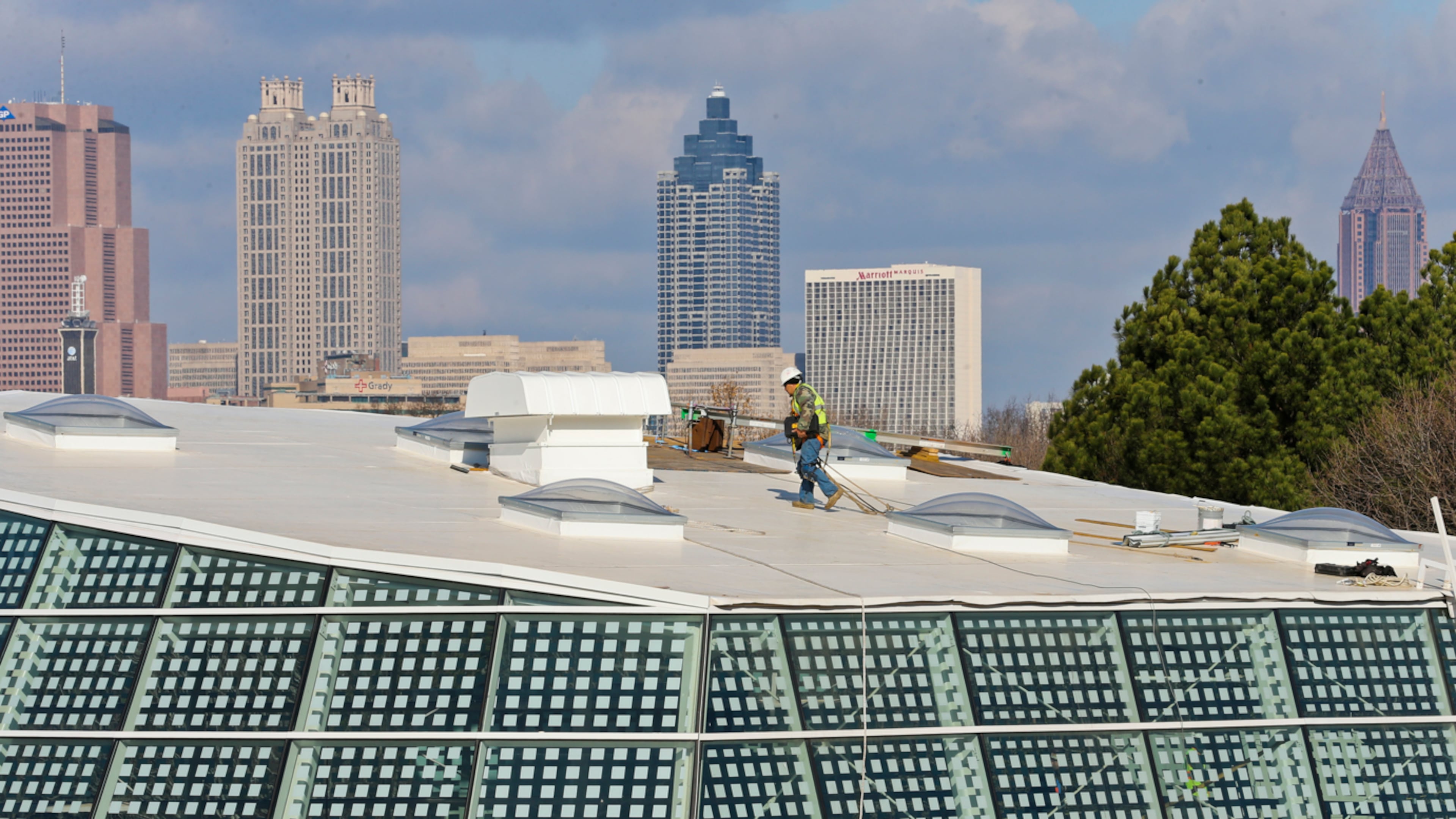 RAISING A REPTILE HOUSE--January 27, 2015 Atlanta: Against the Atlanta skyline - a worker crosses the roofline of the new Scaly Slimy Spectacular: The Amphibian and Reptile Experience, Tuesday, Jan. 27, 2015 at Zoo Atlanta. The $18-million complex will open this spring and be home to more than 60 animal species, including rare Cuban crocodiles. The 111,000 square-foot footprint will incorporate some 9,700 square feet of handcrafted rockwork; 60,000 gallons of water; and a 45-foot glass dome. JOHN SPINK/JSPINK@AJC.COM