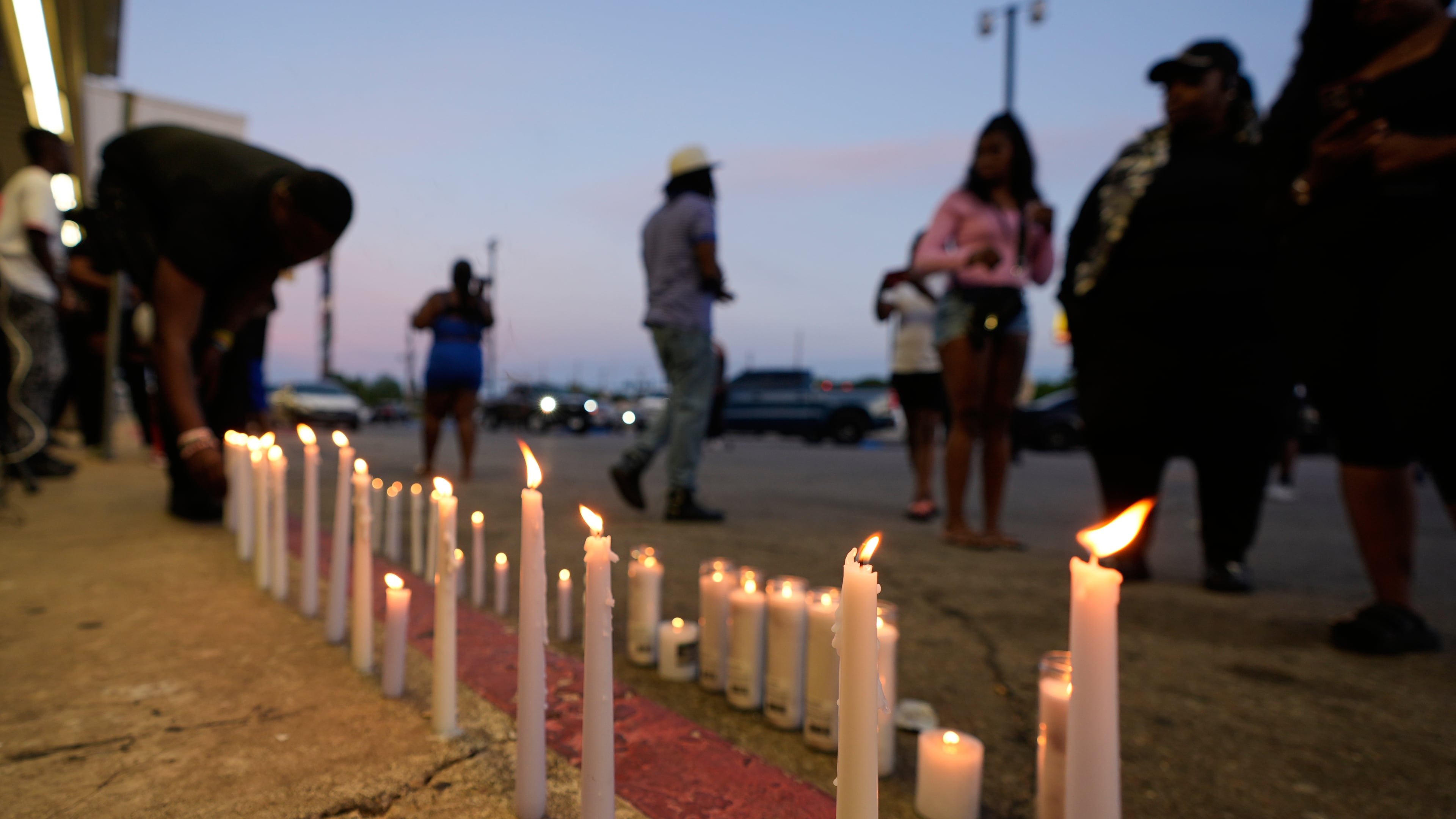A man lights a candle during a prayer vigil for the victims of a mass shooting earlier in the day, Sunday, April 19, 2026, in Shreveport, La. (AP Photo/Gerald Herbert)