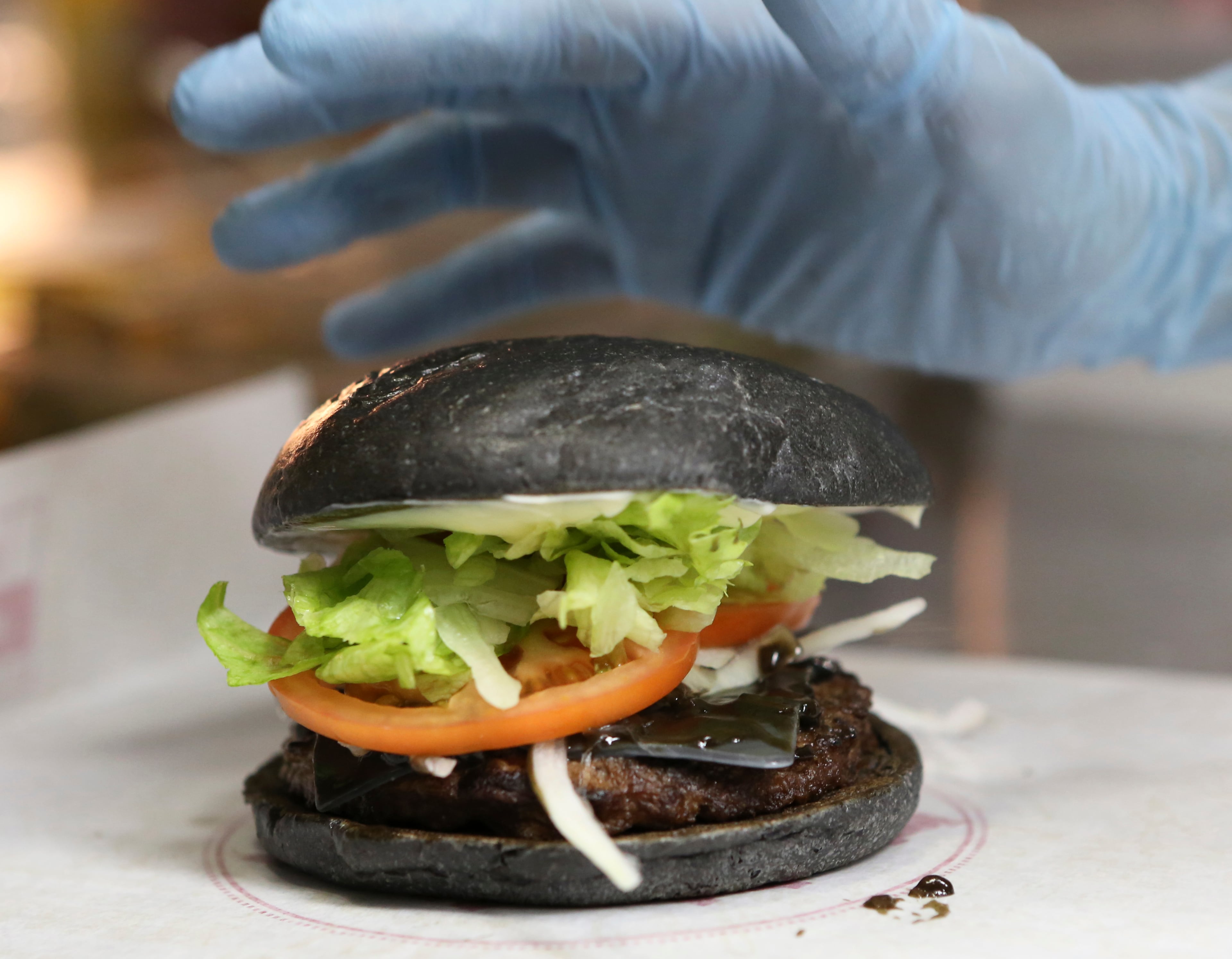 Burger King's new menu Kuro Diamond burger is prepared by employee Rumi Sekine at its Shibuya restaurant in Tokyo Tuesday, Sept. 16, 2014. The international hamburger chain in Japan will launch two new "kuro burger," or "black burger" menus that sport buns, cheese and sauce all in black color, starting on Friday, Sept. 19, for a limited period. The buns and cheese are darkened with bamboo charcoal while the beef patties made with black-pepper are topped with the garlic sauce using squid ink. (AP Photo/Koji Sasahara)