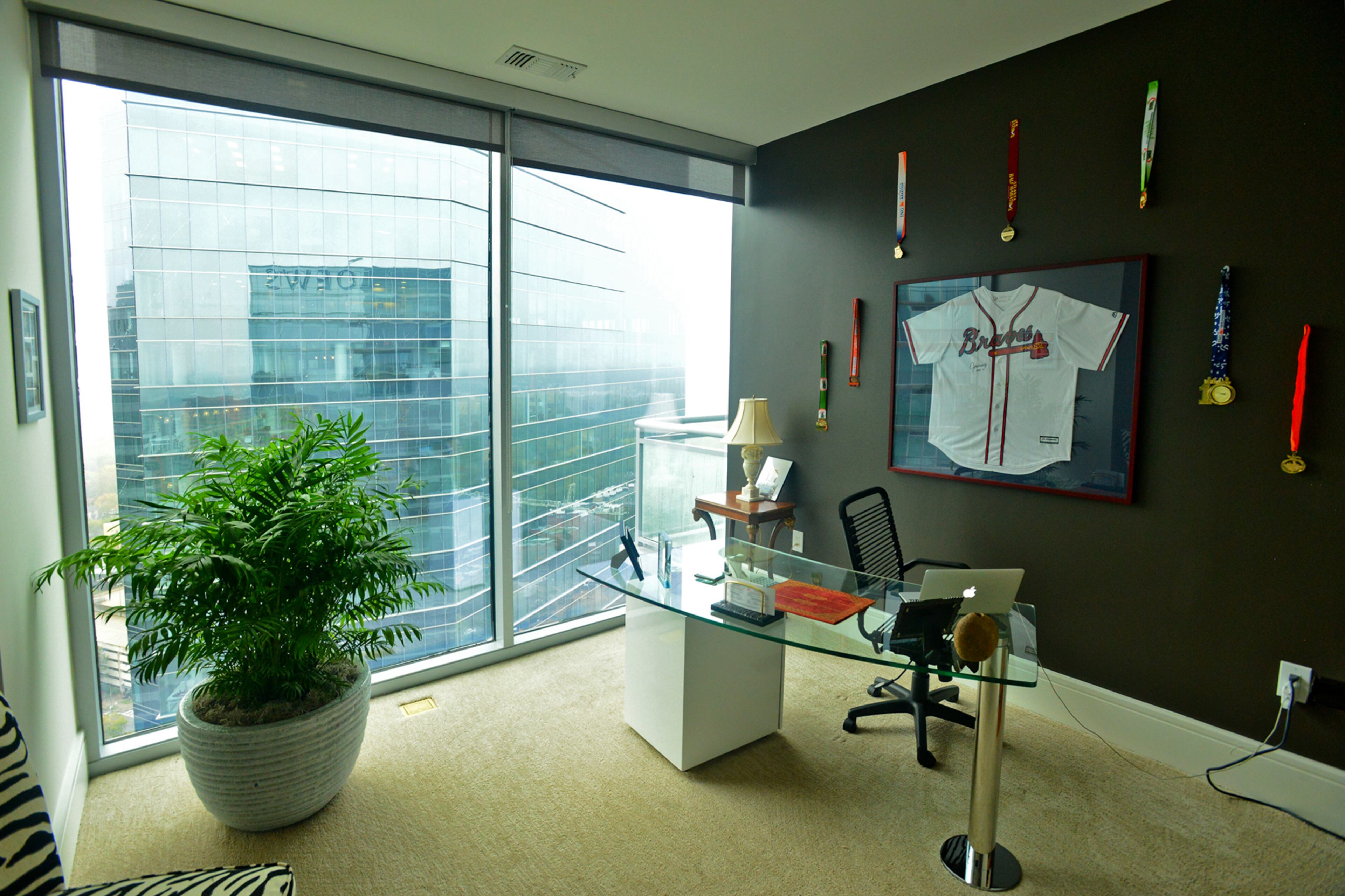The home office, converted from one of the 36th floor's three bedrooms, displays a signed John Smoltz jersey. Homeowner and entrepreneur Jim Wilson brought in a metal and glass desk from By Design Furniture and zebra print chairs from Rooms To Go.