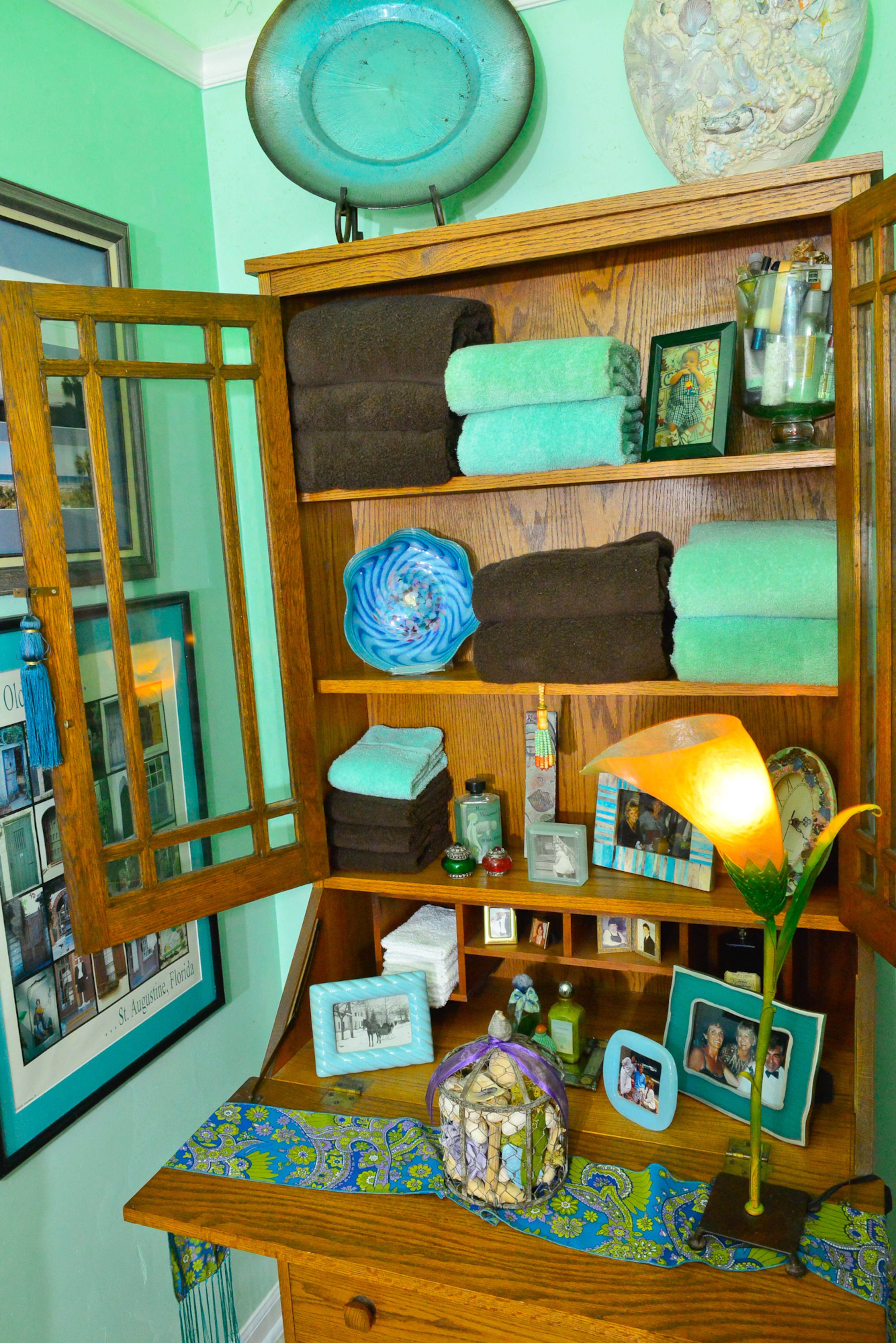An old secretary has a new purpose in the bathroom, storing towels and toiletries. Homeowner Nancy Storey rearranges her furniture and accessories to make the 125-year-old home look new and different. Behr's Canton Jade and Tropical Dream are on the walls.