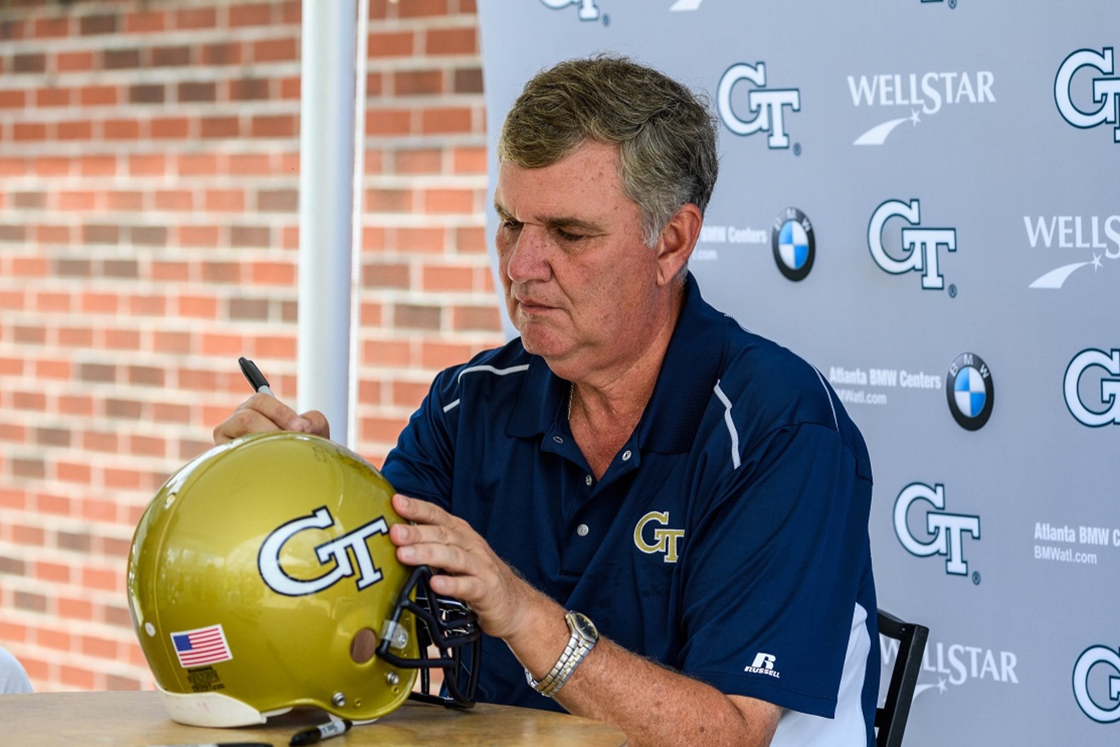 Georgia Tech football coach Paul Johnson autographs a helmet at Fan Day in Bobby Dodd Stadium on Aug. 12, 2017. -- Photo by Danny Karnik/GT Athletics