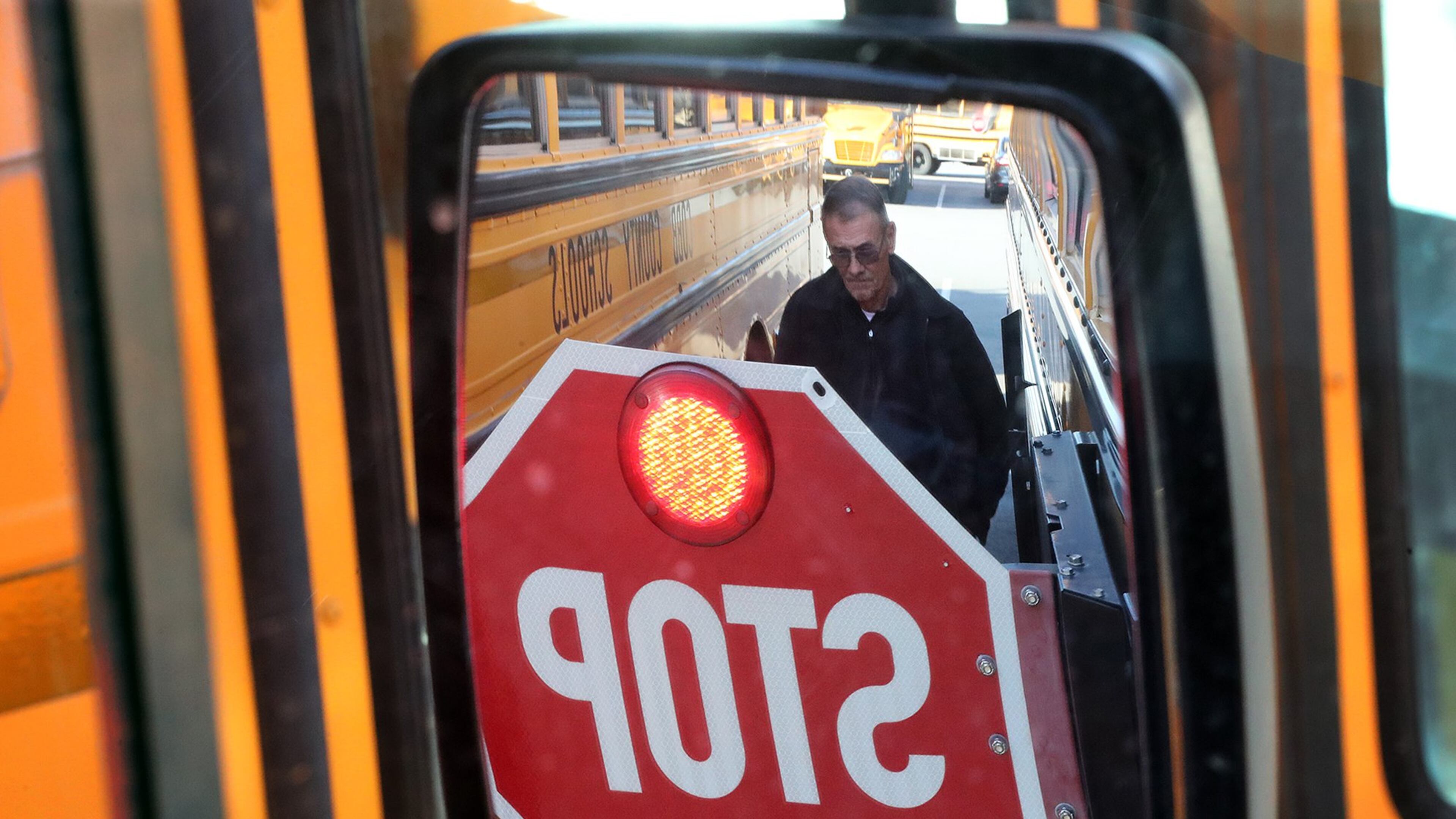 Fleet manager Charles Smith is reflected in a side mirror while going over a detecting system that can warn drivers there is an object near their bus at the Carroll Pitts Jr. Transportation Center in Marietta. Attention to school bus safety has heightened after students were killed in a Chattanooga bus crash. Curtis Compton/ccompton@ajc.com