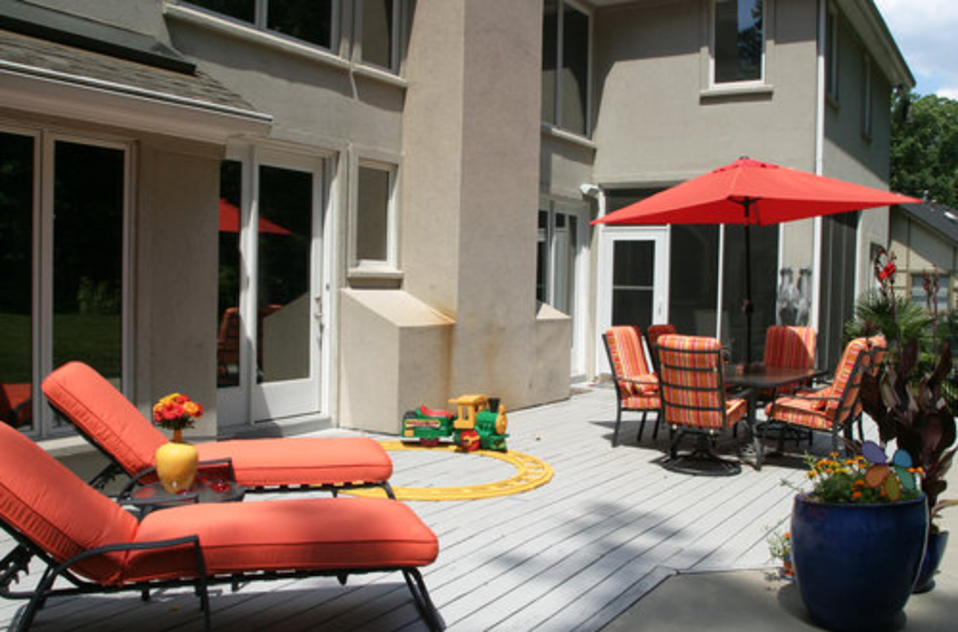 The brightly colored deck furniture contrasts with the home's neutral color scheme.