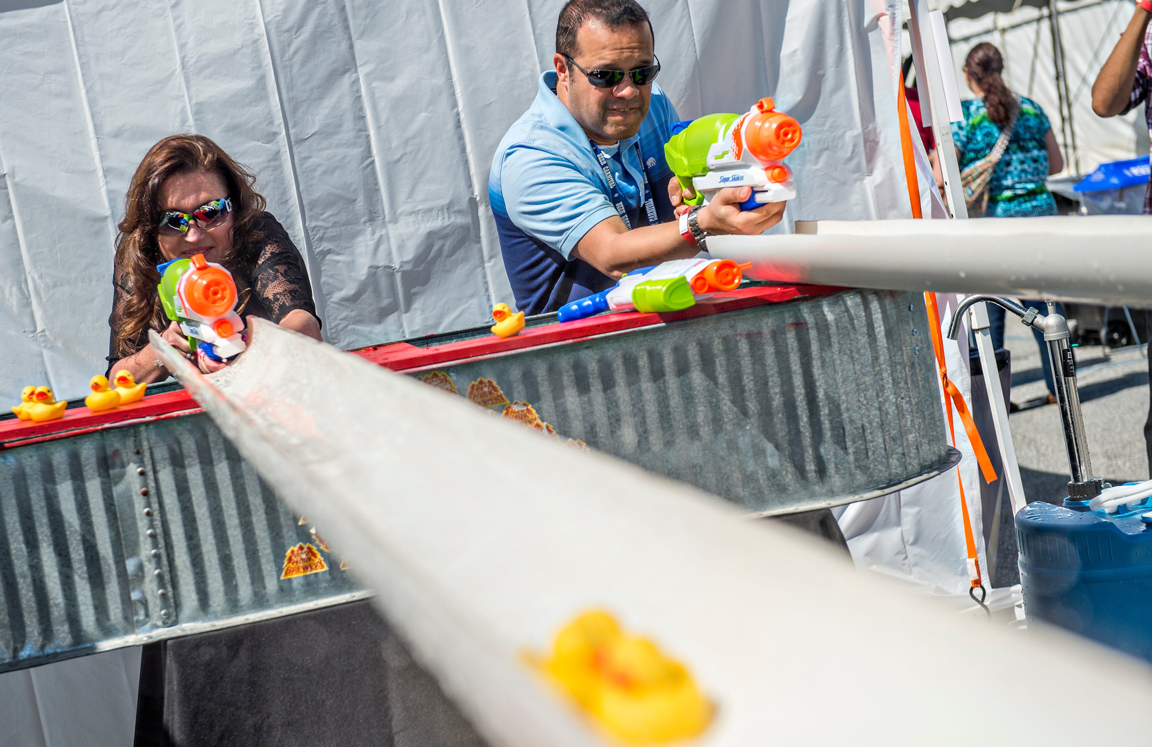 Carla Gullett (left) and Raul Gamez uses water guns to spray rubber ducks down a set of tubes during the sixth annual Beer Carnival at Atlantic Station in downtown Atlanta on Saturday, March 21, 2015. Over 4,000 people attended the event which featured beer from breweries all over the country as well as carnival styled games, food, music and more. JONATHAN PHILLIPS / SPECIAL