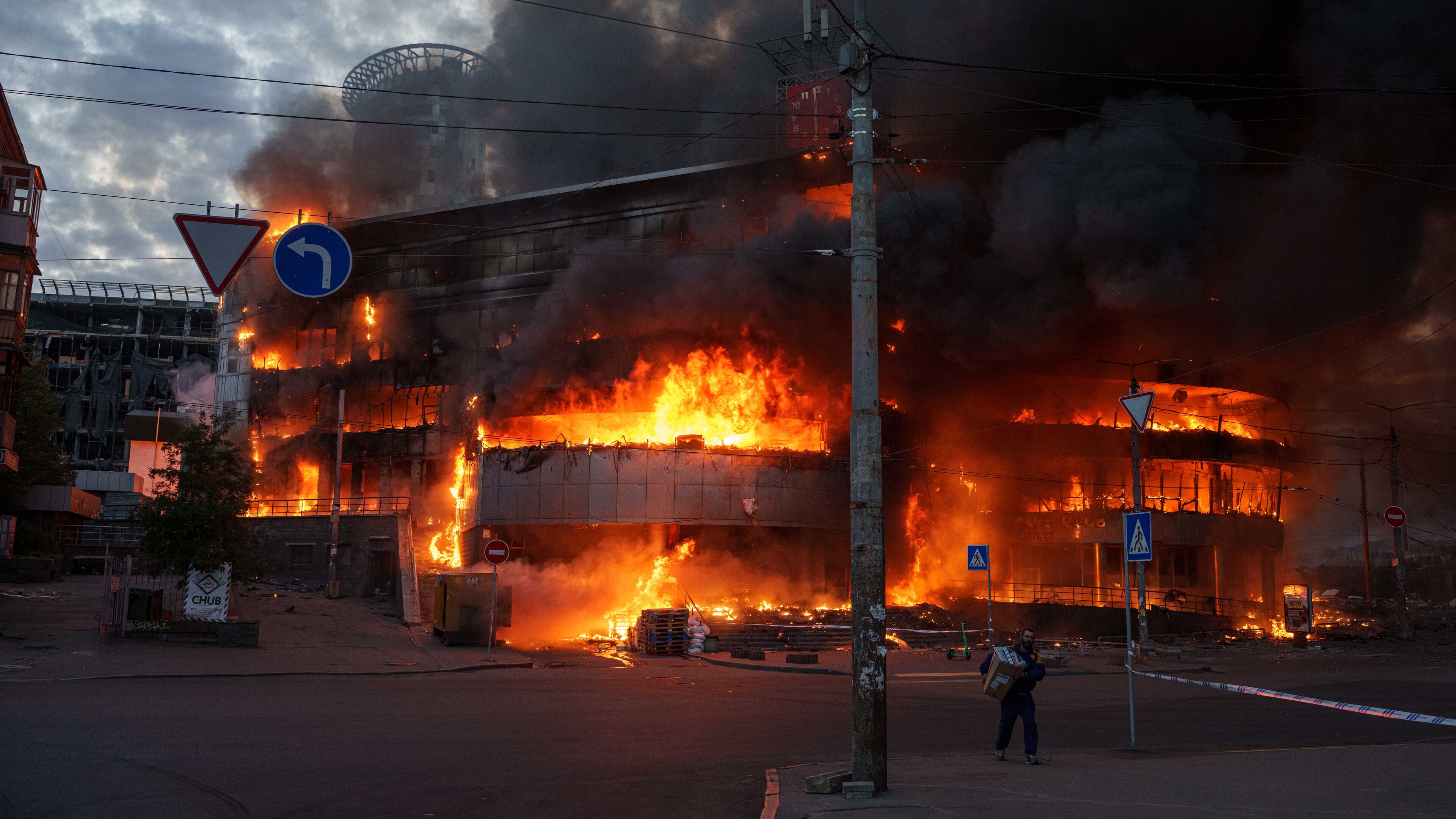 A man carries a box from a burning trade center after a Russian strike on Kyiv, Ukraine, on Sunday, May 24, 2026. (AP Photo/Evgeniy Maloletka)