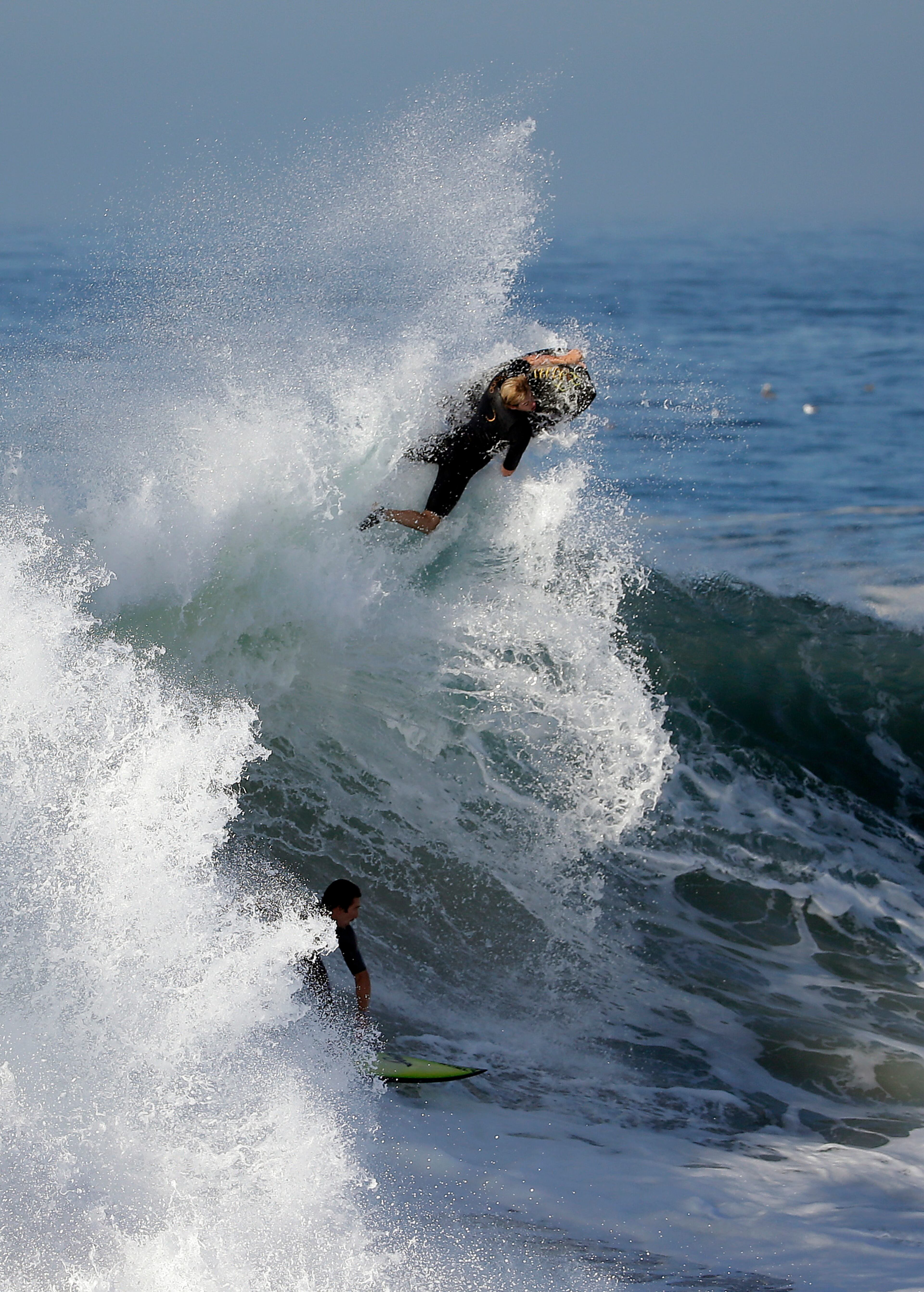 A bogie boarder and a surfer ride a wave at the wedge, on Wednesday, Aug. 27, 2014 in Newport Beach, Calif. Beach goers experienced much higher than normal surf, brought on by Hurricane Marie spinning off the coast of Mexico. (AP Photo/Chris Carlson)