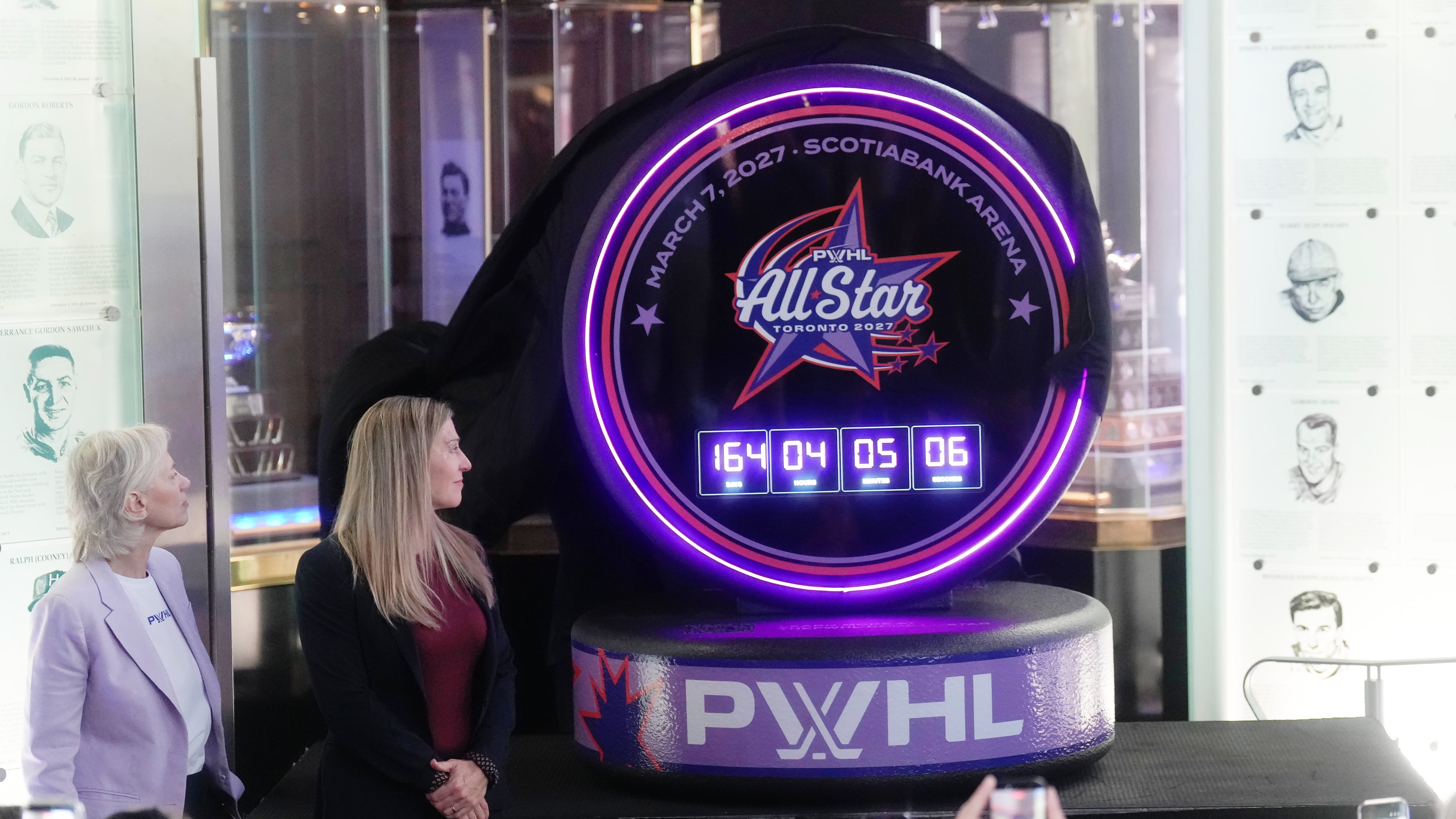 Jayna Hefford, second from left, Executive Vice President of Hockey Operations for the PWHL, and Amy Scheer, left, PWHL Executive Vice President of Business Operations, unveils the logo for the first ever PWHL All-Star-Game which will take place in Toronto next year during a press conference in Toronto, Thursday, Sept. 24, 2026. (Nathan Denette/The Canadian Press via AP)