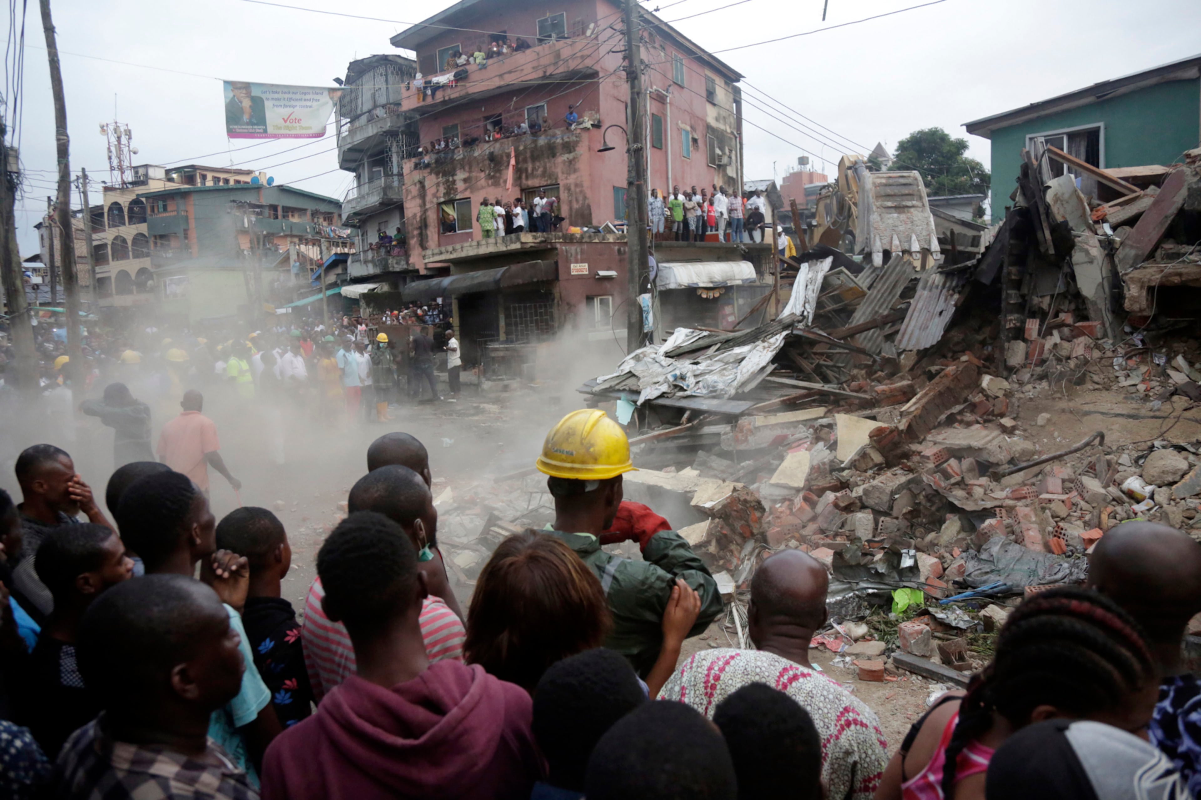 Onlookers watch as rescue workers search for survivors at the rubbles of a collapsed building in a densely populated neighborhood in Lagos, Nigeria Tuesday, July 25, 2017. Rescue work is still ongoing. (AP Photo/Sunday Alamba)