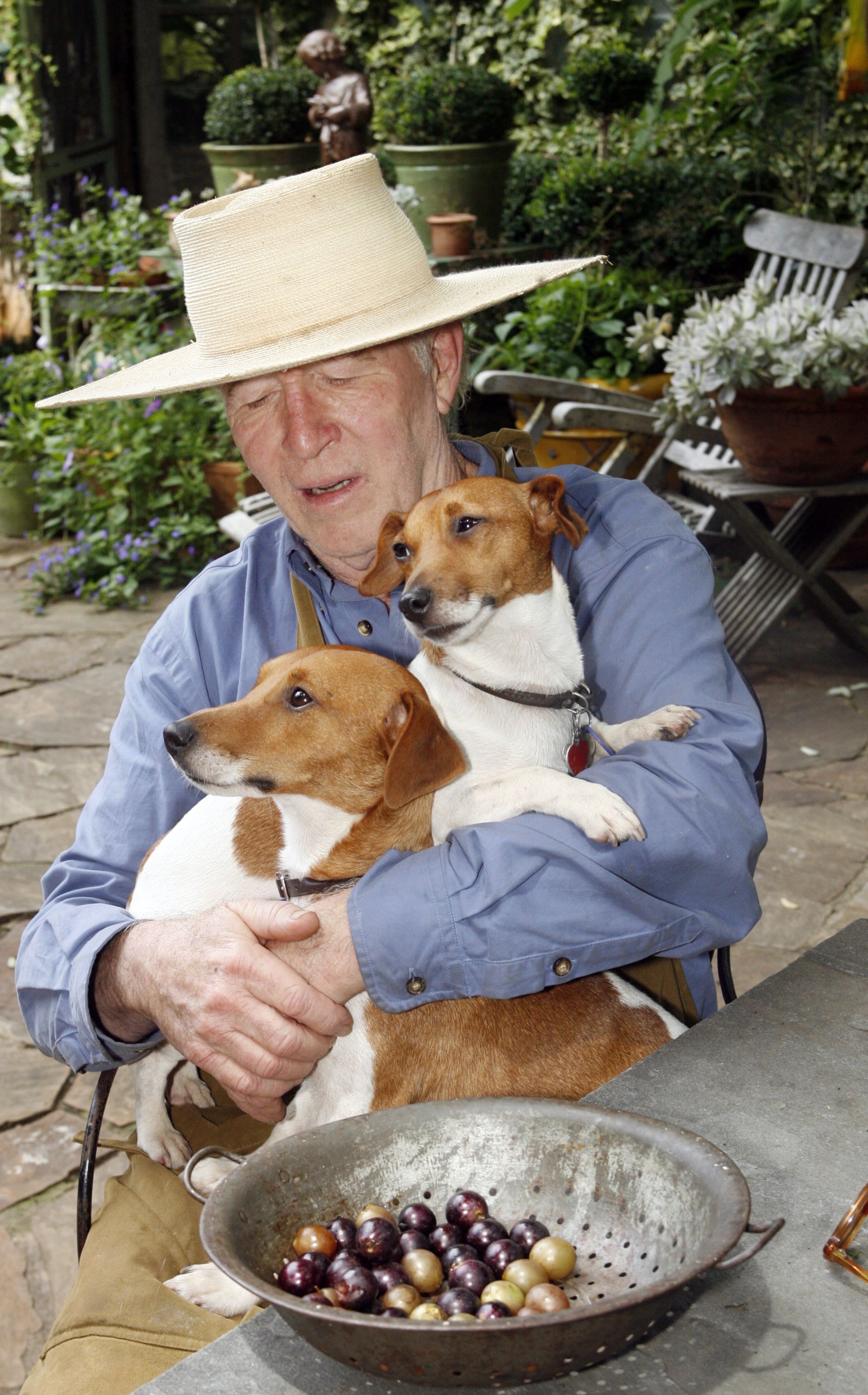 Popcorn & Cecil sits in Ryan Gainey's lap as he talks about his two muscadine arbors at his Decatur home. Staff photo