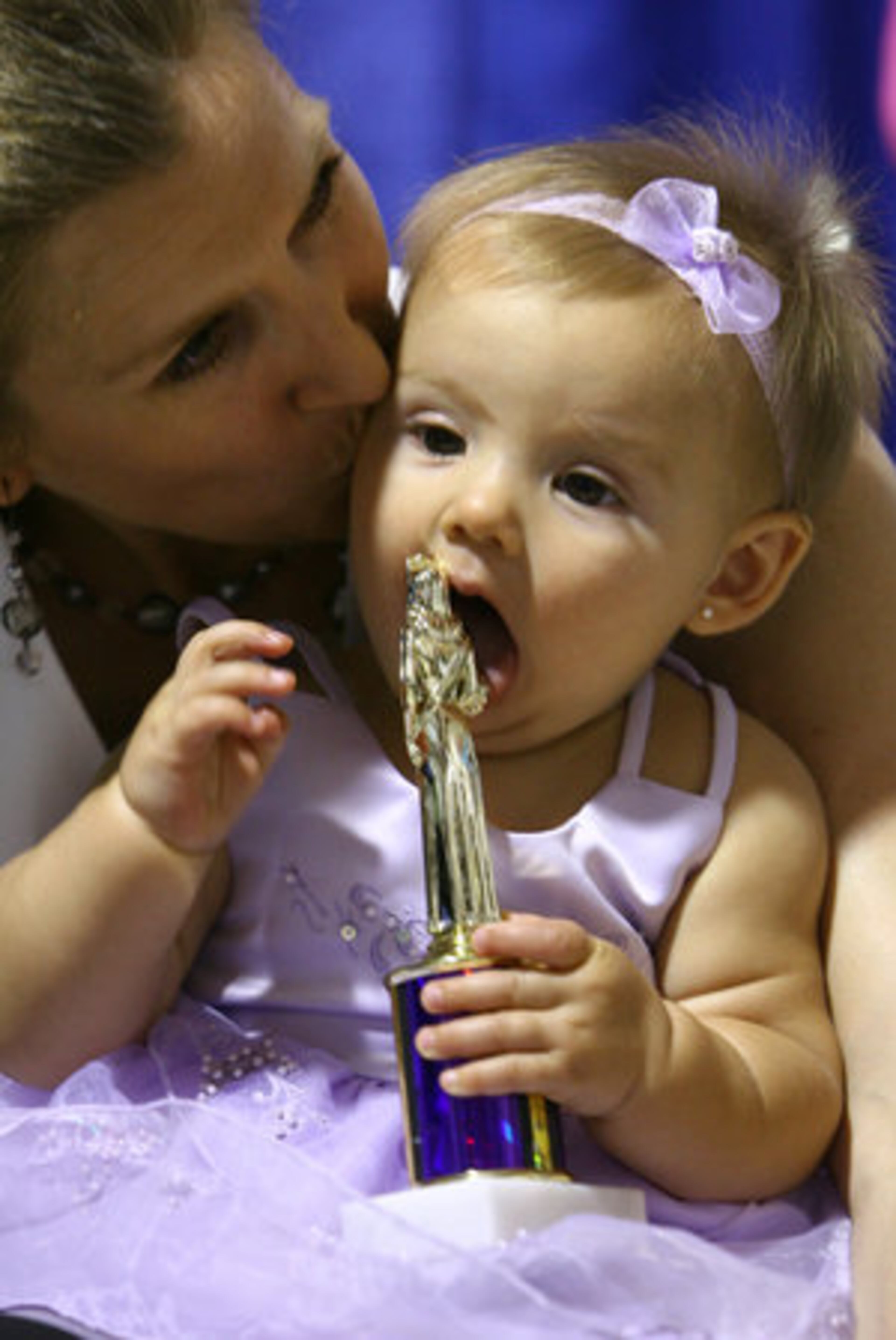 Little Haley Fowler chews on her participant trophy backstage with her mother, Rachel Fowler. Haley also won the People's Choice trophy.