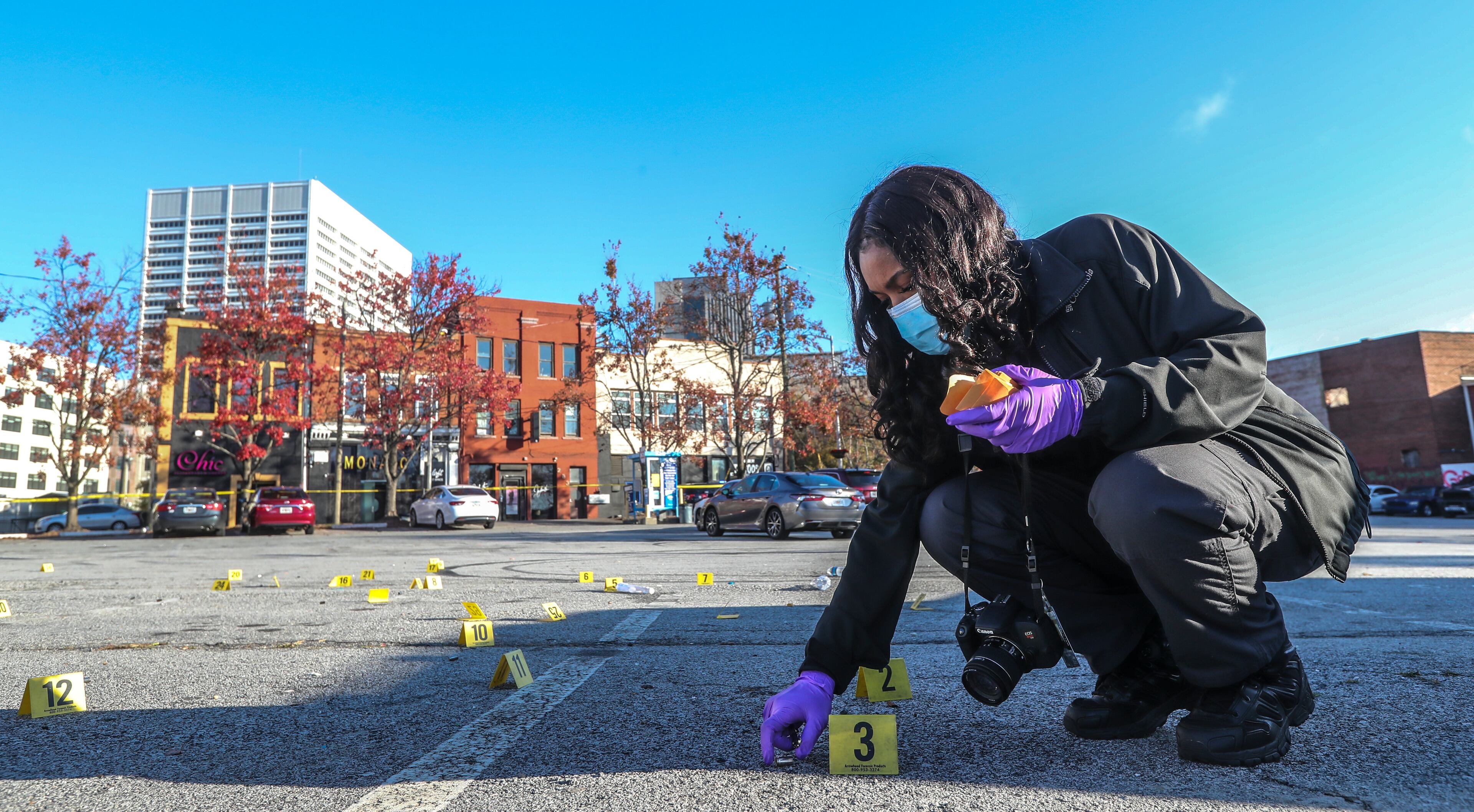 Atlanta Police Crime Technician K. Gallagher collects dozens of shell casings following a shooting outside a downtown Atlanta hookah lounge. (John Spink / John.Spink@ajc.com)