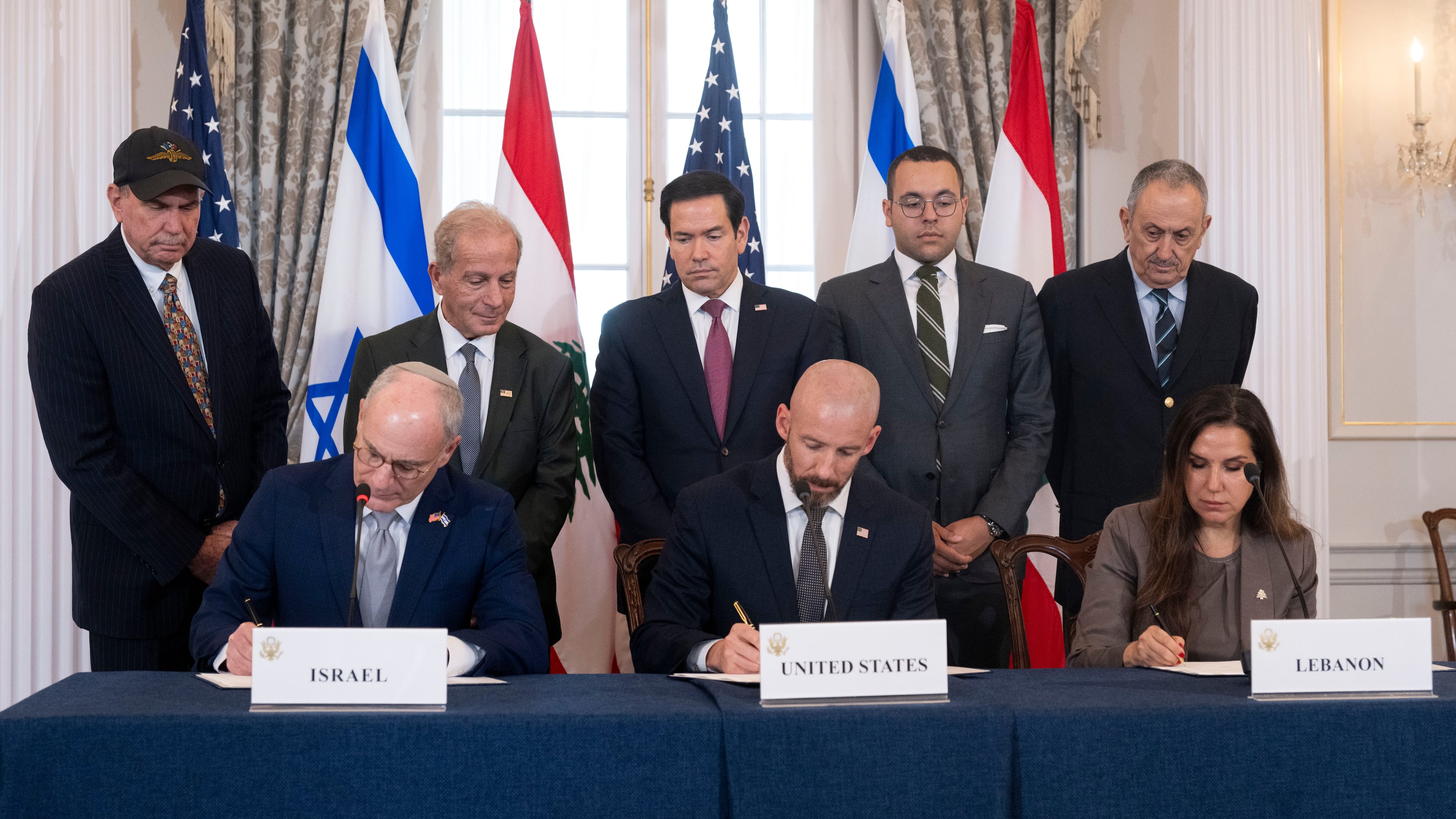 Secretary of State Marco Rubio and others watch, seated from left, Israel's Ambassador to the U.S. Yechiel Leiter, counselor Dan Holler, and Lebanon's Ambassador to the U.S. Nada Hamadeh, sign a framework agreement, described as a first step toward peace following months of conflict between Israel and the Lebanese militant group Hezbollah, at the State Department, Friday, June 26, 2026, in Washington. (AP Photo/Kevin Wolf)