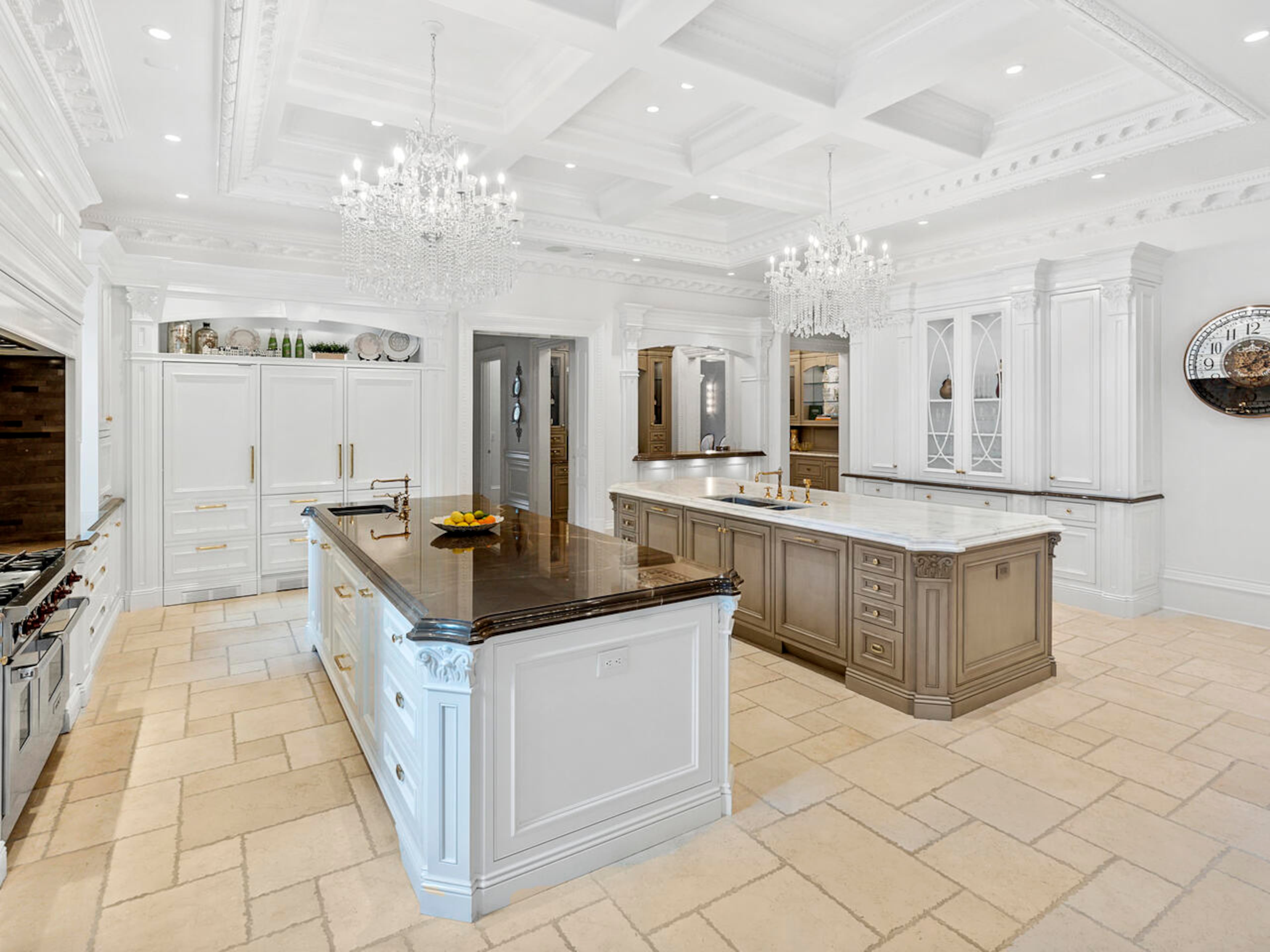 The kitchen features double Calacatta Gold marble islands and the latest professional-grade Wolf and SubZero appliances and multiple sinks for preparing meals. The kitchen opens to a breakfast room, family room, full bar, and accesses the formal dining room.