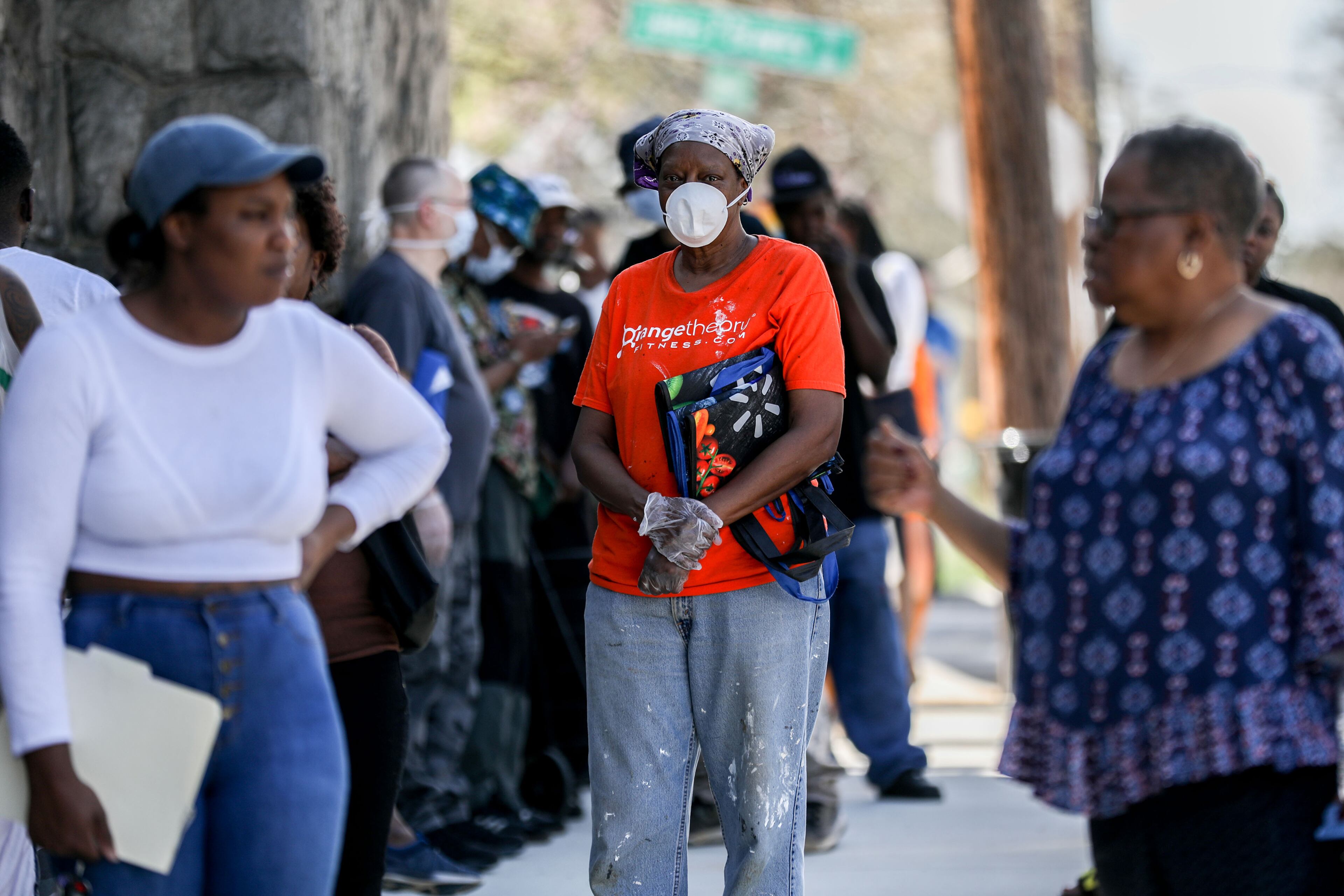 A woman wears a mask while waiting in line to receive free groceries at the first of five pop-up grocery store locations provided by The Atlanta Hawks, Goodr, and State Farm at At-Promise Youth Center during the COVID-19 crisis, Friday, March 20, 2020. BRANDEN CAMP/SPECIAL