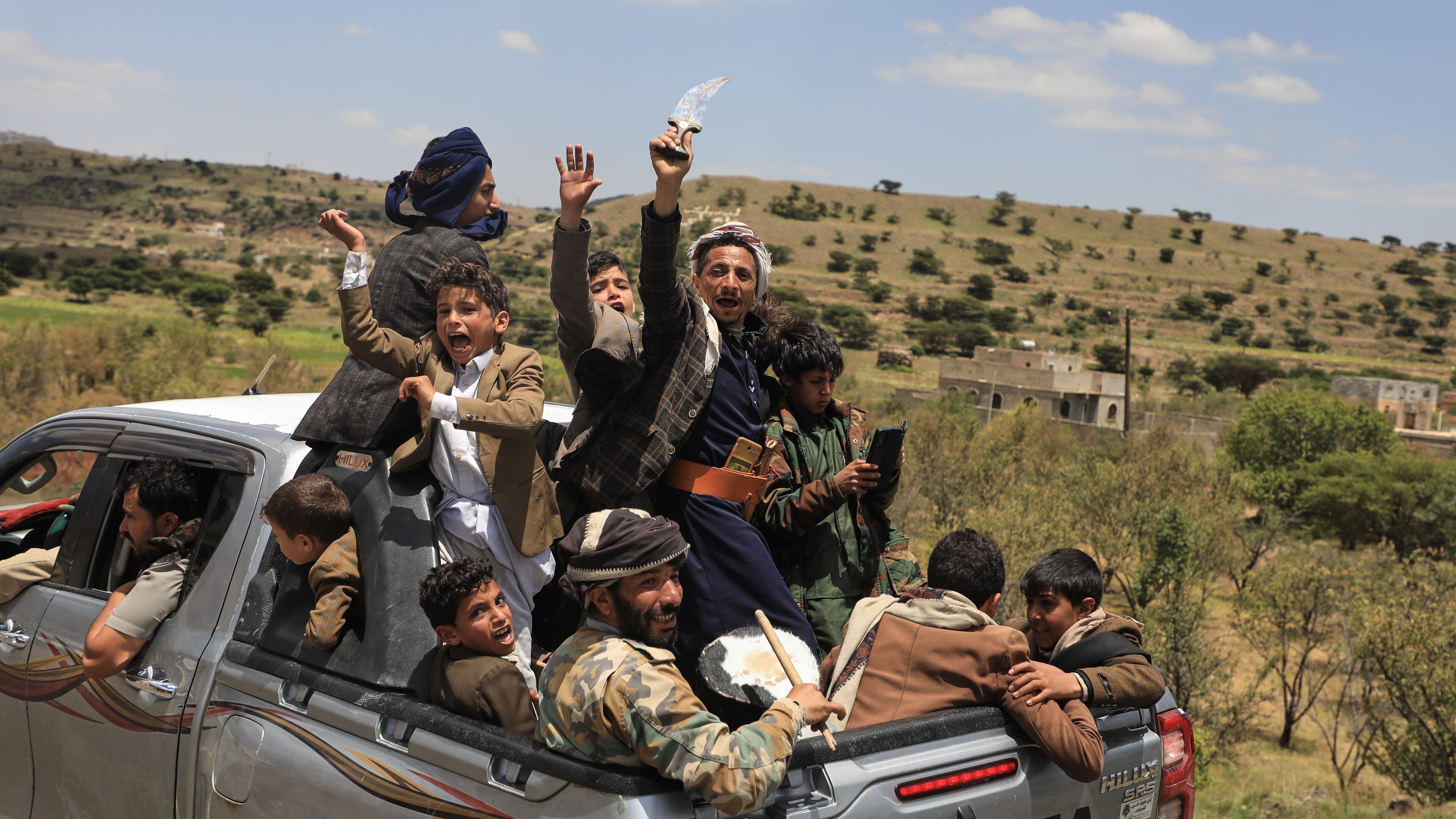 Yemeni civilians celebrate while riding in the back of a pickup truck in the Bani Matar district, Yemen, Saturday, Sept. 12, 2026, as they follow a convoy carrying Houthi prisoners freed in Mokha on its way to Sanaa following the Houthi takeover of the southern Red Sea port city. (AP Photo/STR)