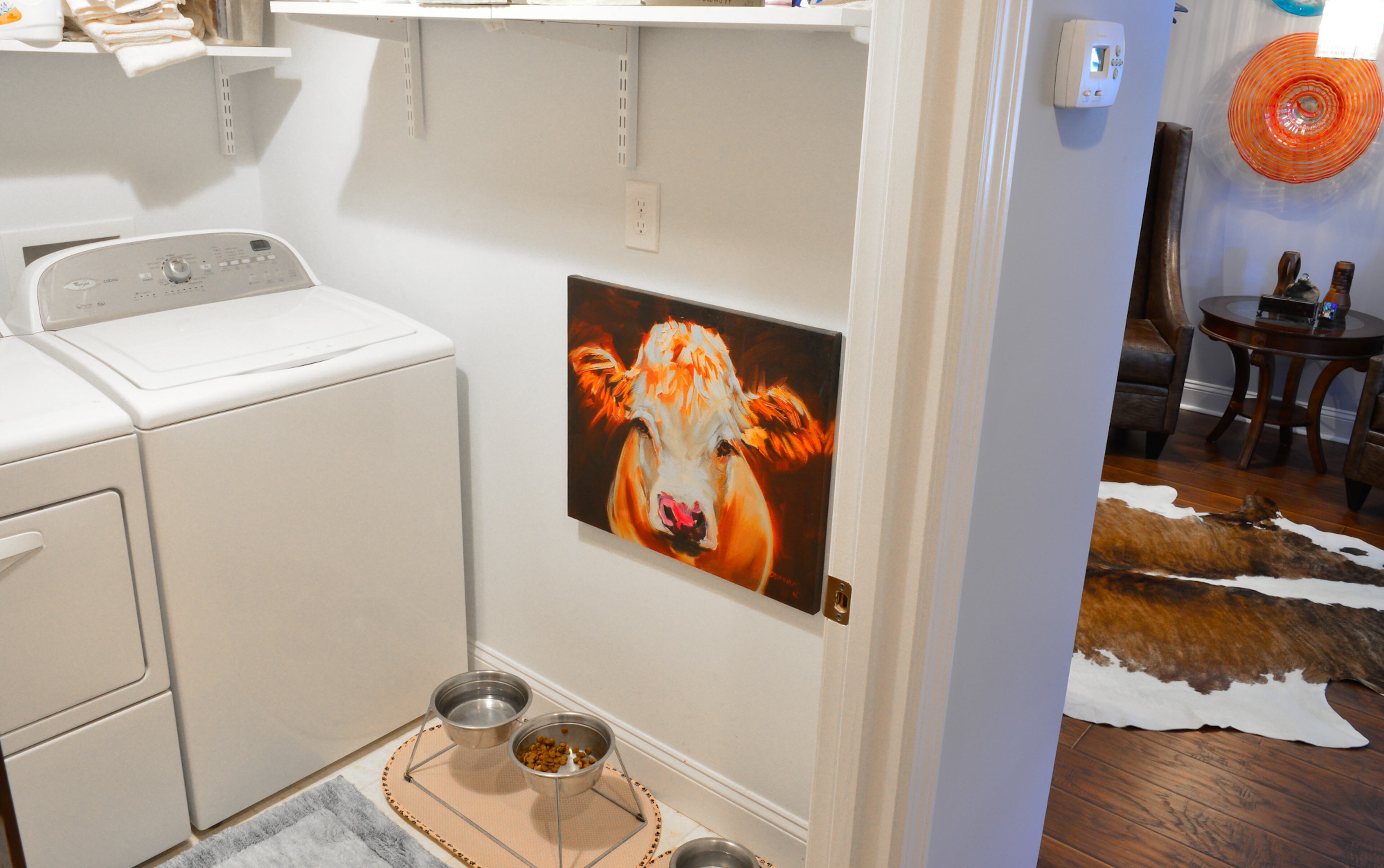 Homeowner Michael Bush said the laundry room was about the size of a closet before he and fellow homeowner Johnny Mitchell remodeled the 1952 home, tearing down walls and increasing the size of the laundry room. The couple's taste in art continues with this painting of a cow in the laundry room.