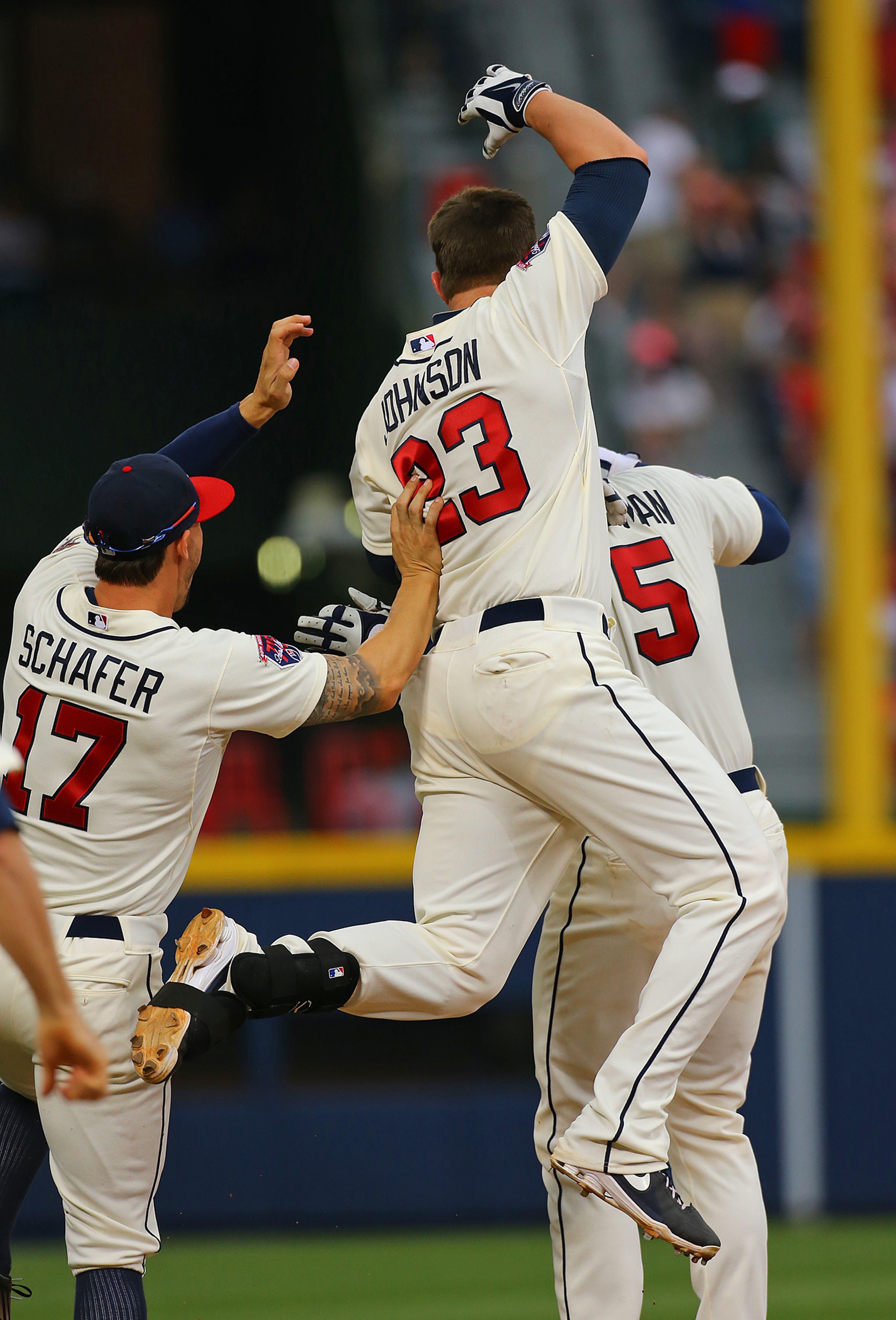 Jordan Schafer (left) and Chris Johnson jump on Freddie Freeman (right) after Freeman hit a game winning RBI single to beat the Reds 1-0 in the 10th inning. CURTIS COMPTON / CCOMPTON@AJC.COM