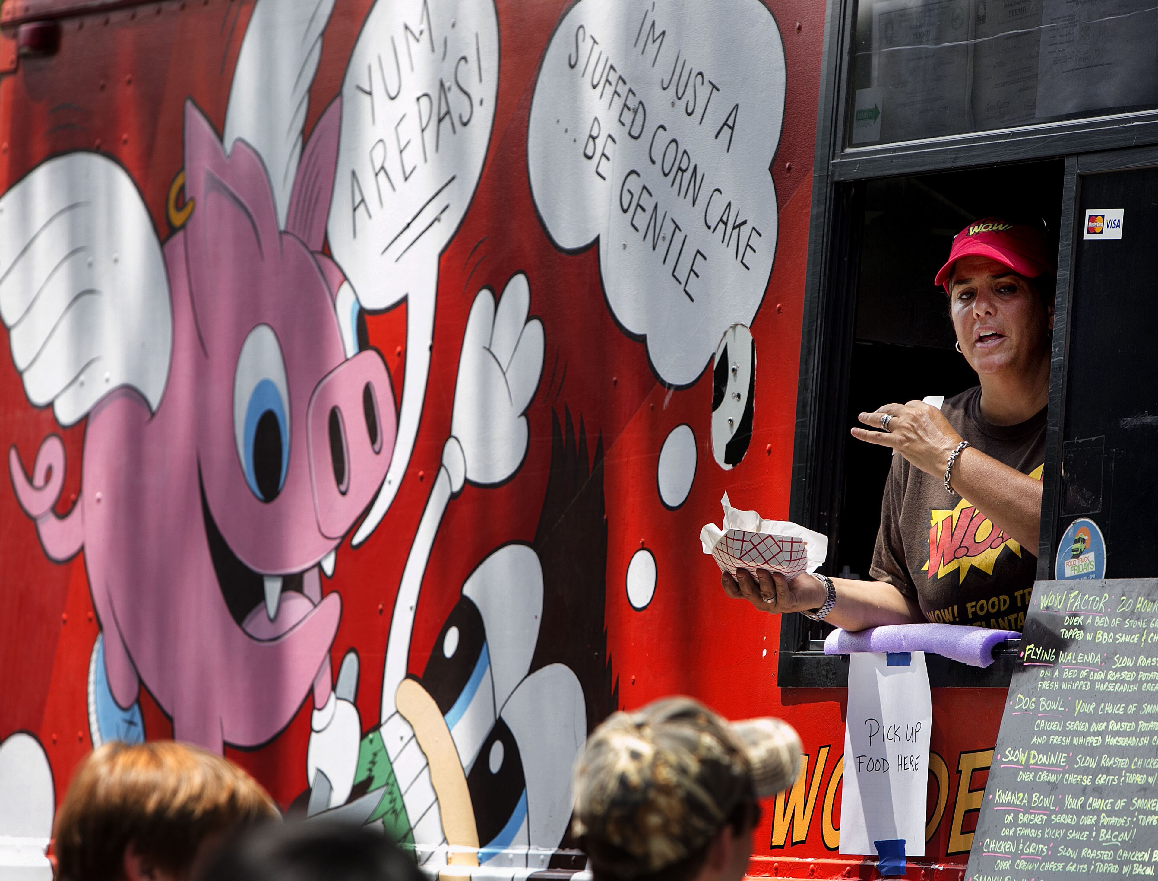 Wendy Cross served up food from the Wow! Food truck at the third annual Atlanta Street Food Festival at Piedmont Park in Atlanta on Saturday July 12, 2014. Presented by MARTA, the event proceeds will support the Giving kitchen, which provides crisis grants to members of Atlanta's restaurant community facing unanticipated hardship. More than 40 food trucks lined the park's walkway to offer a wide variety of cuisine. (Photo by Phil Skinner)