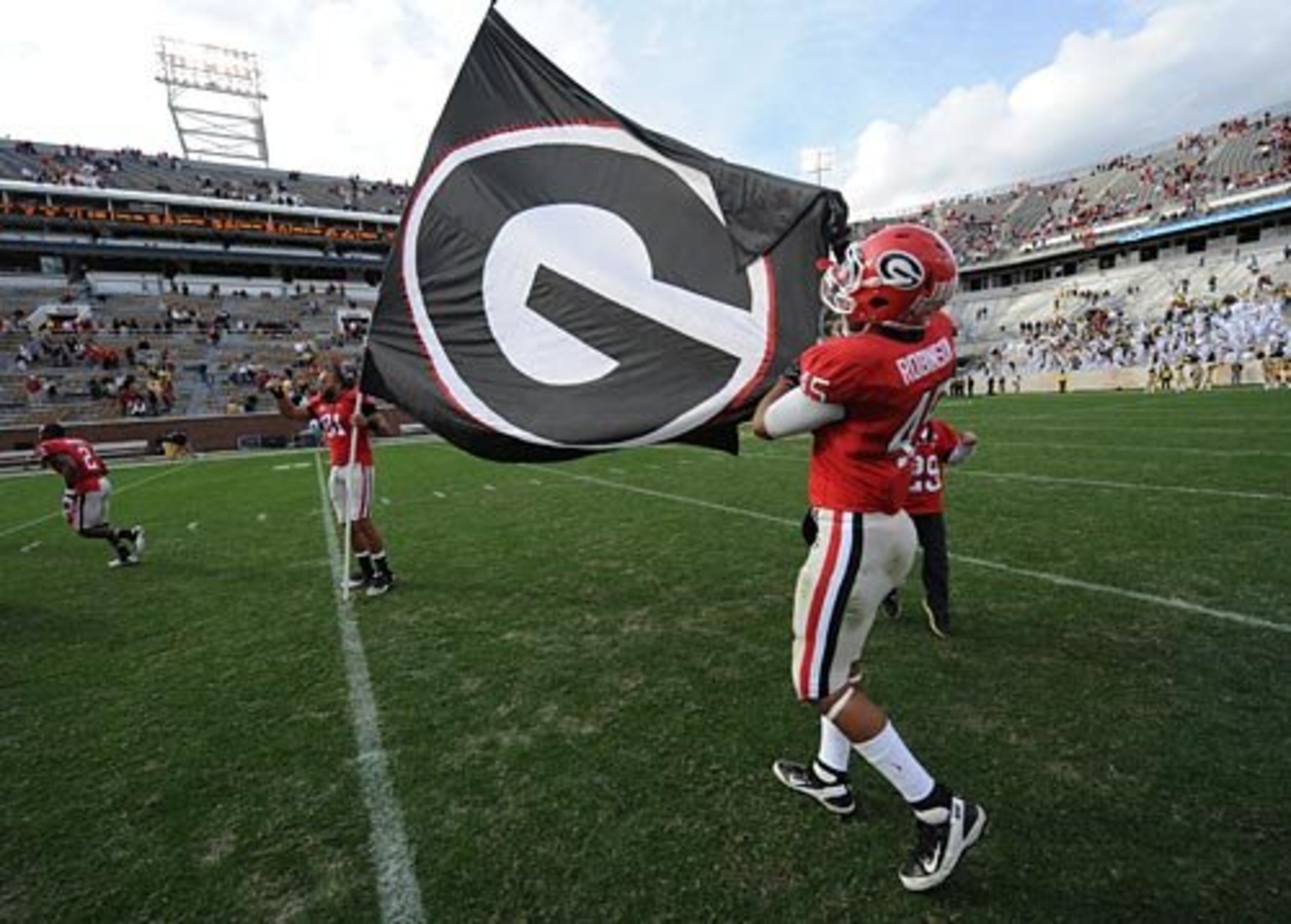 UGA's Aron White (81) and Christian Robinson (45) plant the Georgia "G" flag in Grant Field at Georgia Tech following the Bulldogs' victory.