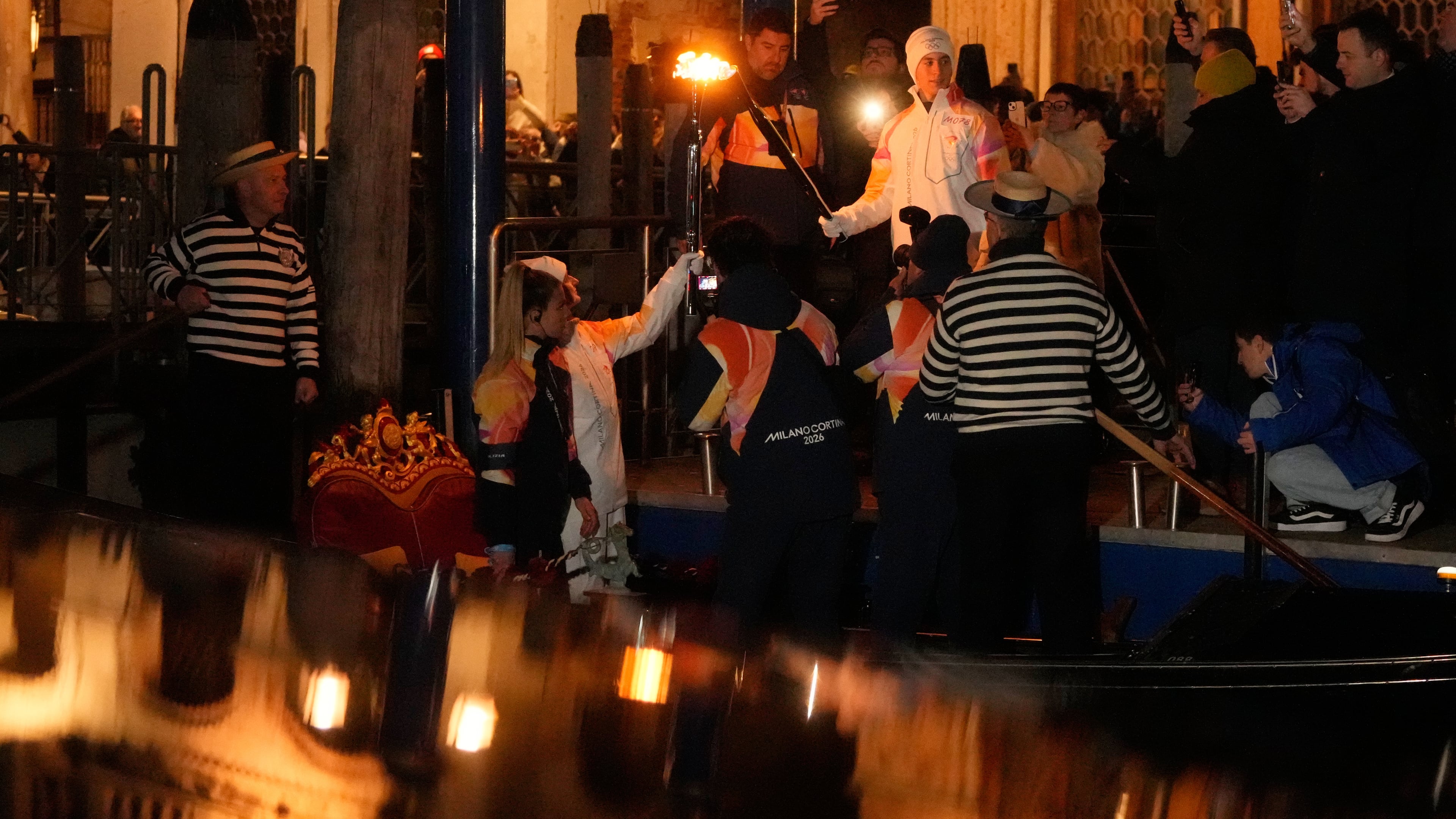 Torchbearers hold the Olympic torches flame on the Grand Canal in Venice, Italy, Thursday, Jan. 22, 2026, its journey will conclude in Milan on February 6 for the Winter Olympics opening ceremony. (AP Photo/Luca Bruno)