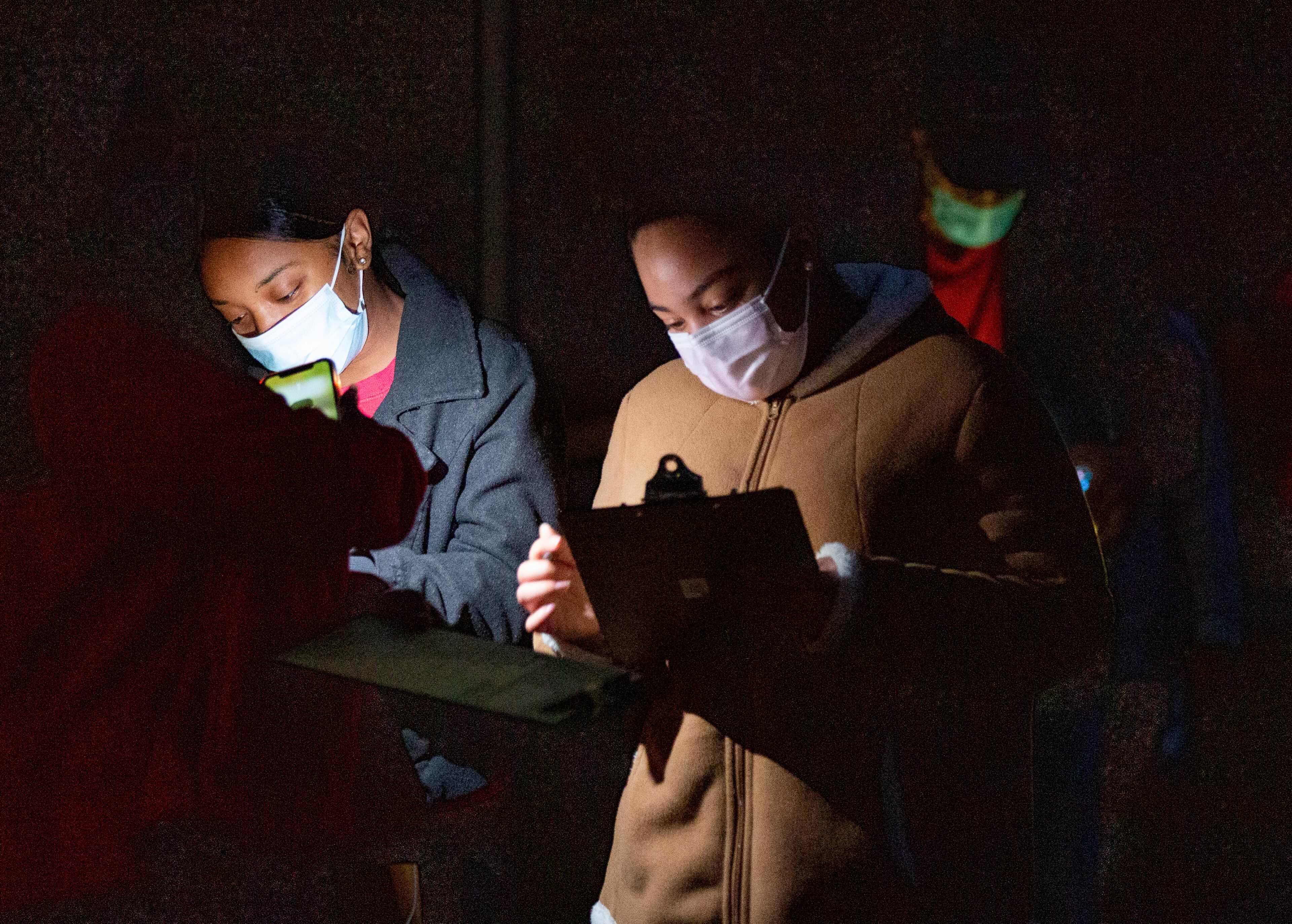 People fill out forms by the light of their phones while waiting in line to vote at Shorty Howell Park in Gwinnett on Saturday, October 24, 2020. STEVE SCHAEFER / SPECIAL TO THE AJC