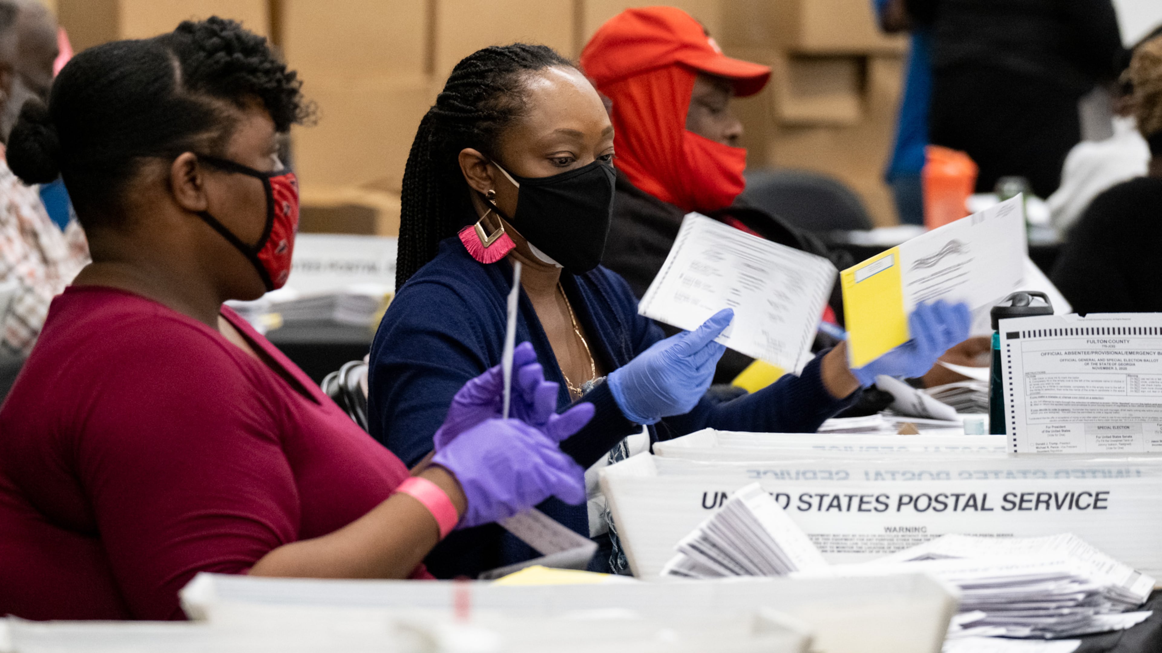 Workers sort mail-in and drop-off ballots at the Fulton County sorting center at State Farm Arena on Tuesday evening, Nov. 3, 2020, just before polls closed. (Ben Gray for the AJC)