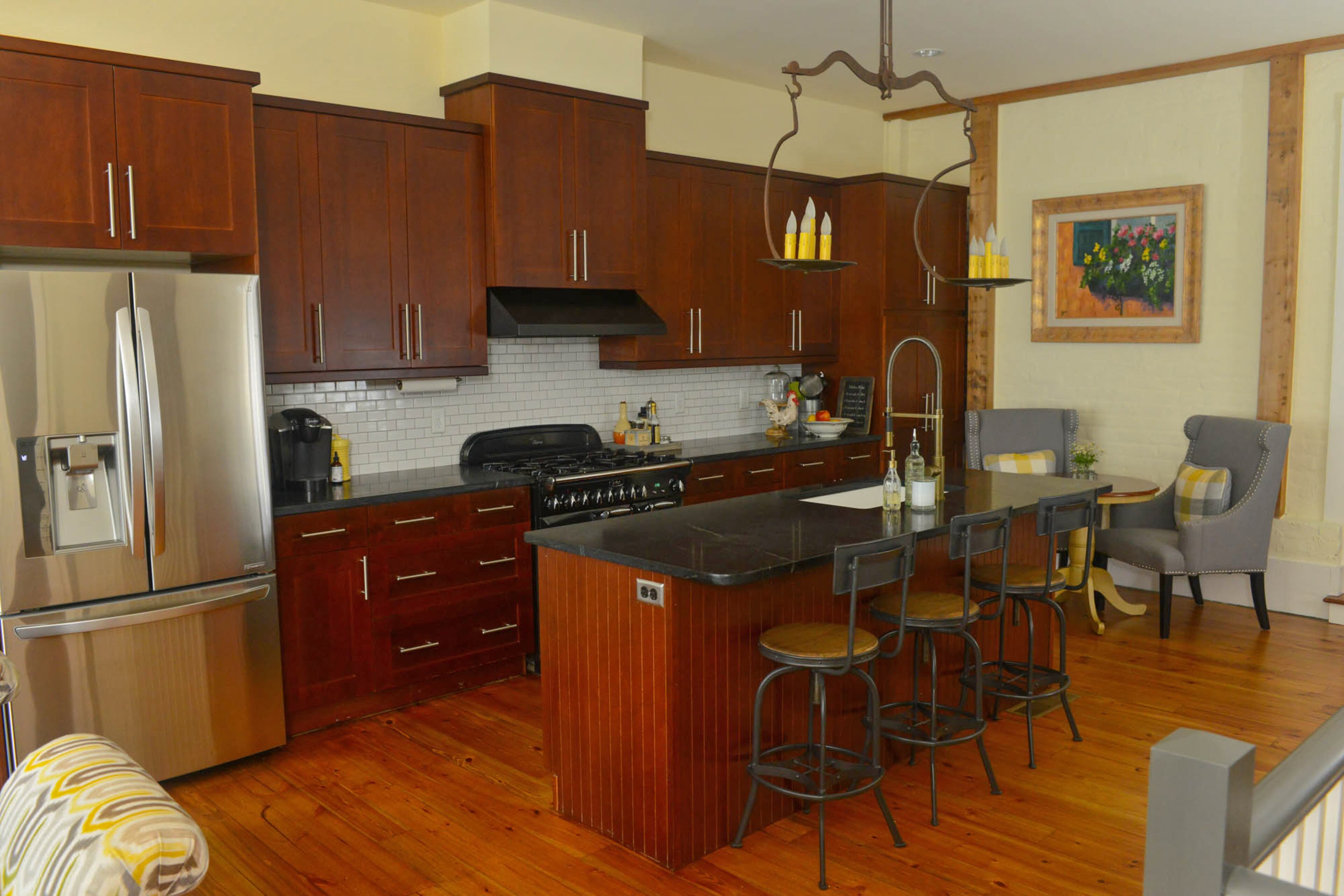 The floor boards throughout the Roswell home came from a farmhouse in Marietta, but are original to the mid-1800s time period. In contrast, the kitchen provides modern details like mini subway tiles above the AGA range. The light above the island was moved from the den to the kitchen during renovations and is from a Parisian flea market. Stools are Ballard Design are tucked under the island, which has a faucet from California Faucets.