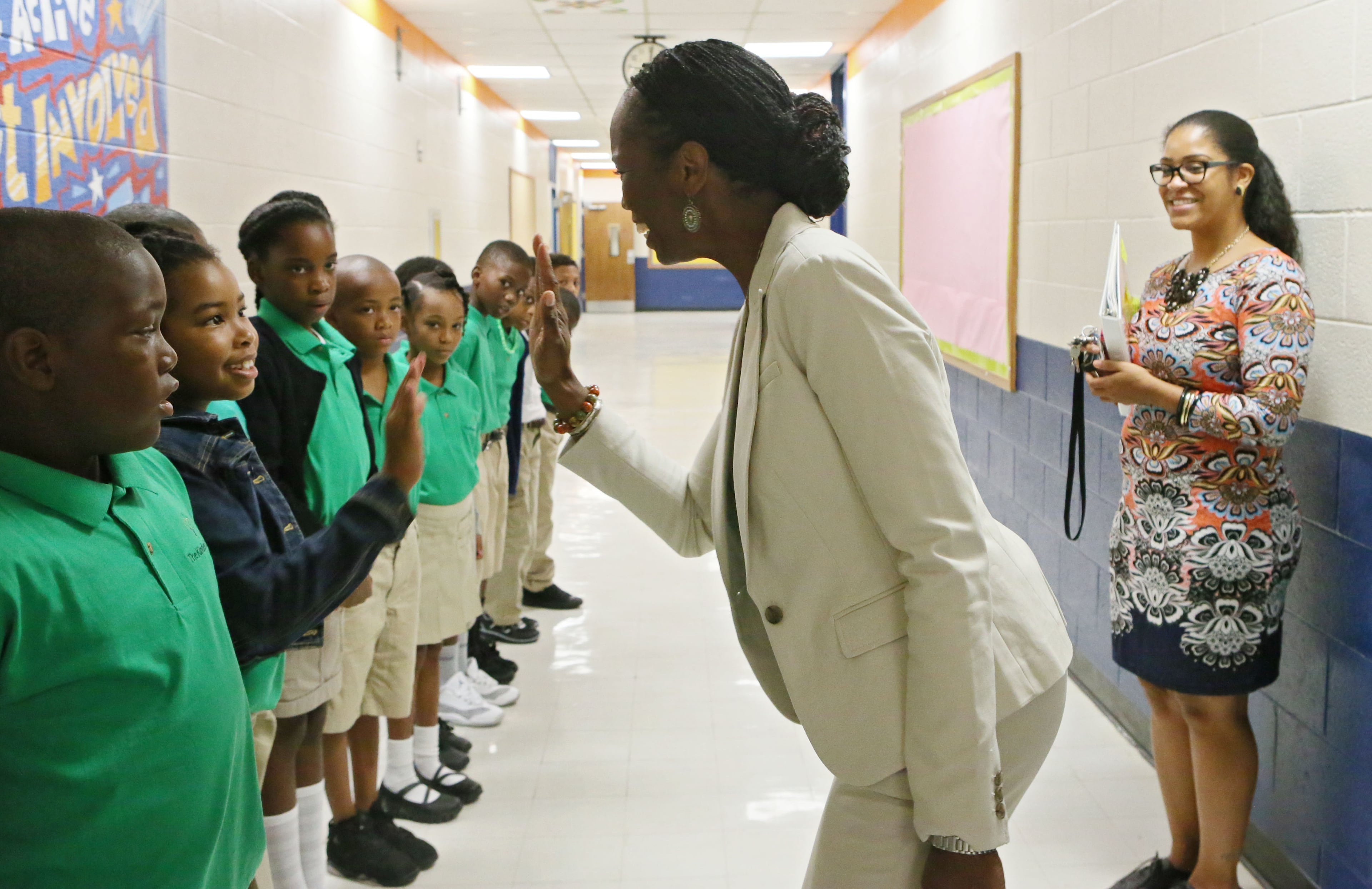 Principal Gilberte Pascal high fives students as they tour the school and learn procedures. The new operator, who met with success at the first Kindezi campus across town, has high hopes for this new elementary school, near a homeless shelter and a trashed park in Atlanta's Old Fourth Ward.