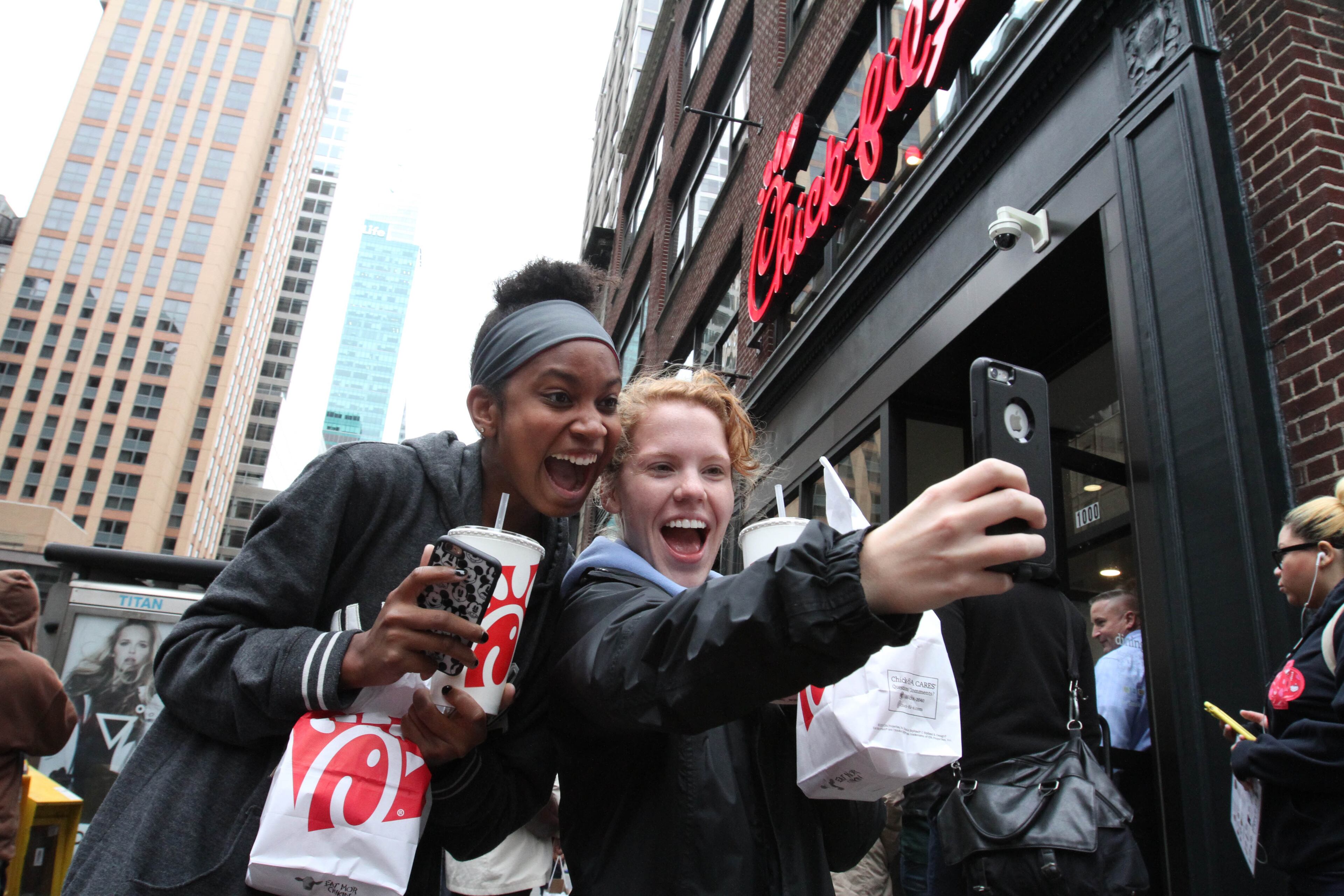 Jaimie Cranford, right, takes a photograph with Mariah Reives outside the Chick-fil-A store in New York on the store's opening day Saturday Oct. 3, 2015. Cranford, originally from South Carolina, and Reives, originally from North Carolina, currently live in New York. (AP Photo/Tina Fineberg)