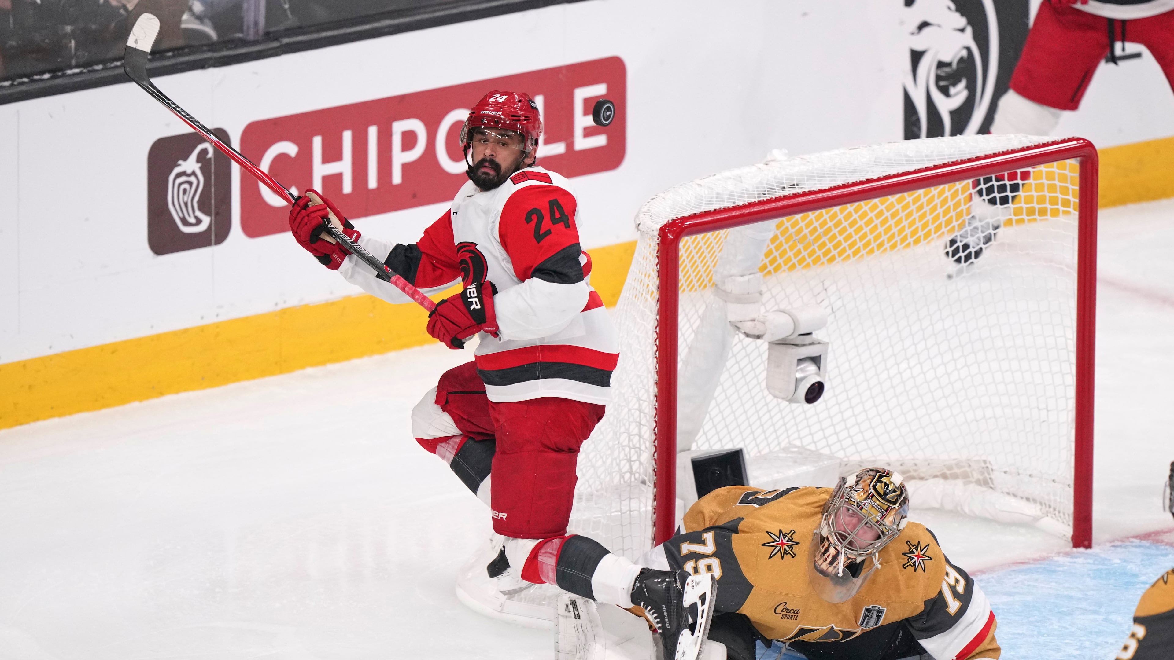 FILE - Carolina Hurricanes right wing Seth Jarvis, left, tries to know a the puck out of the air as Vegas Golden Knights goaltender Carter Hart defends during the third period in Game 4 of the NHL hockey Stanley Cup Final series June 9, 2026, in Las Vegas. (AP Photo/Candice Ward, File)