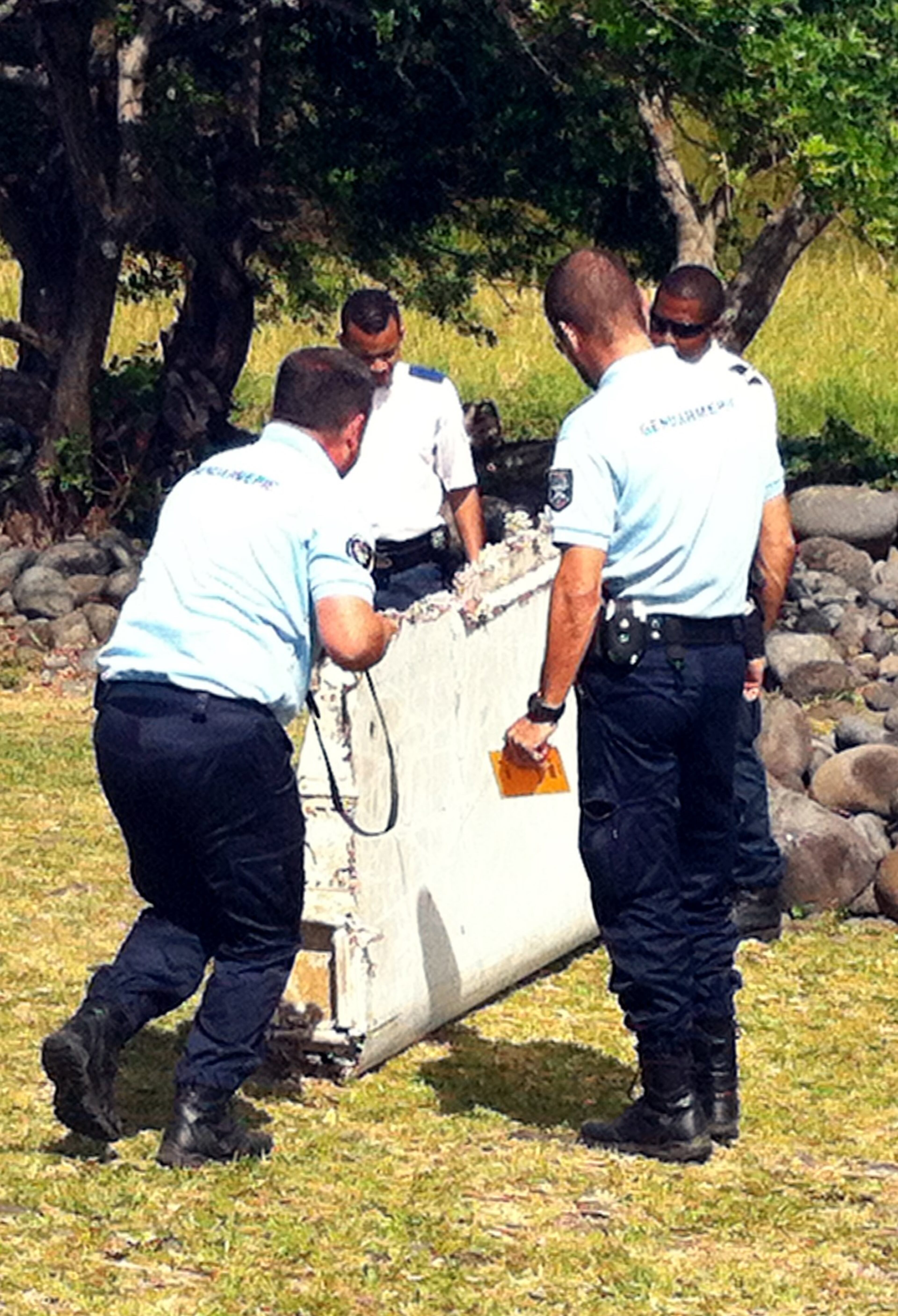 Policemen and gendarmes stand next to a piece of debris from an unidentified aircraft found in the coastal area of Saint-Andre de la Reunion, in the east of the French Indian Ocean island of La Reunion, on July 29, 2015. The two-metre-long debris, which appears to be a piece of a wing, was found by employees of an association cleaning the area and handed over to the air transport brigade of the French gendarmerie (BGTA), who have opened an investigation. An air safety expert did not exclude it could be a part of the Malaysia Airlines flight MH370, which went missing in the Indian Ocean on March 8, 2014. (Photo: YANNICK PITOU/AFP/Getty Images)