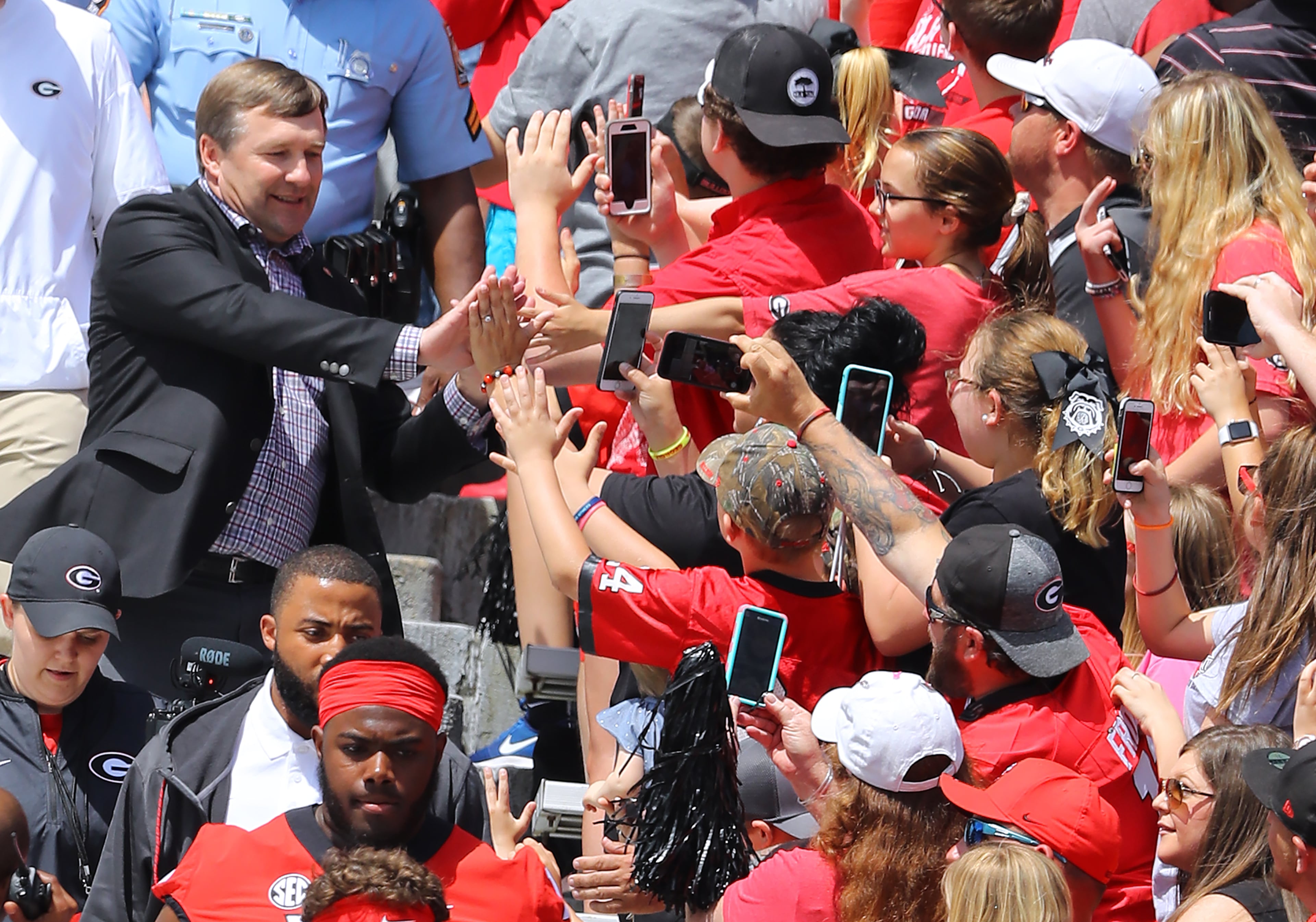 Kirby Smart high fives some fans while others film his entry into Sanford Stadium Saturday prior to Georgia's G-Day game. Curtis Compton/ccompton@ajc.com