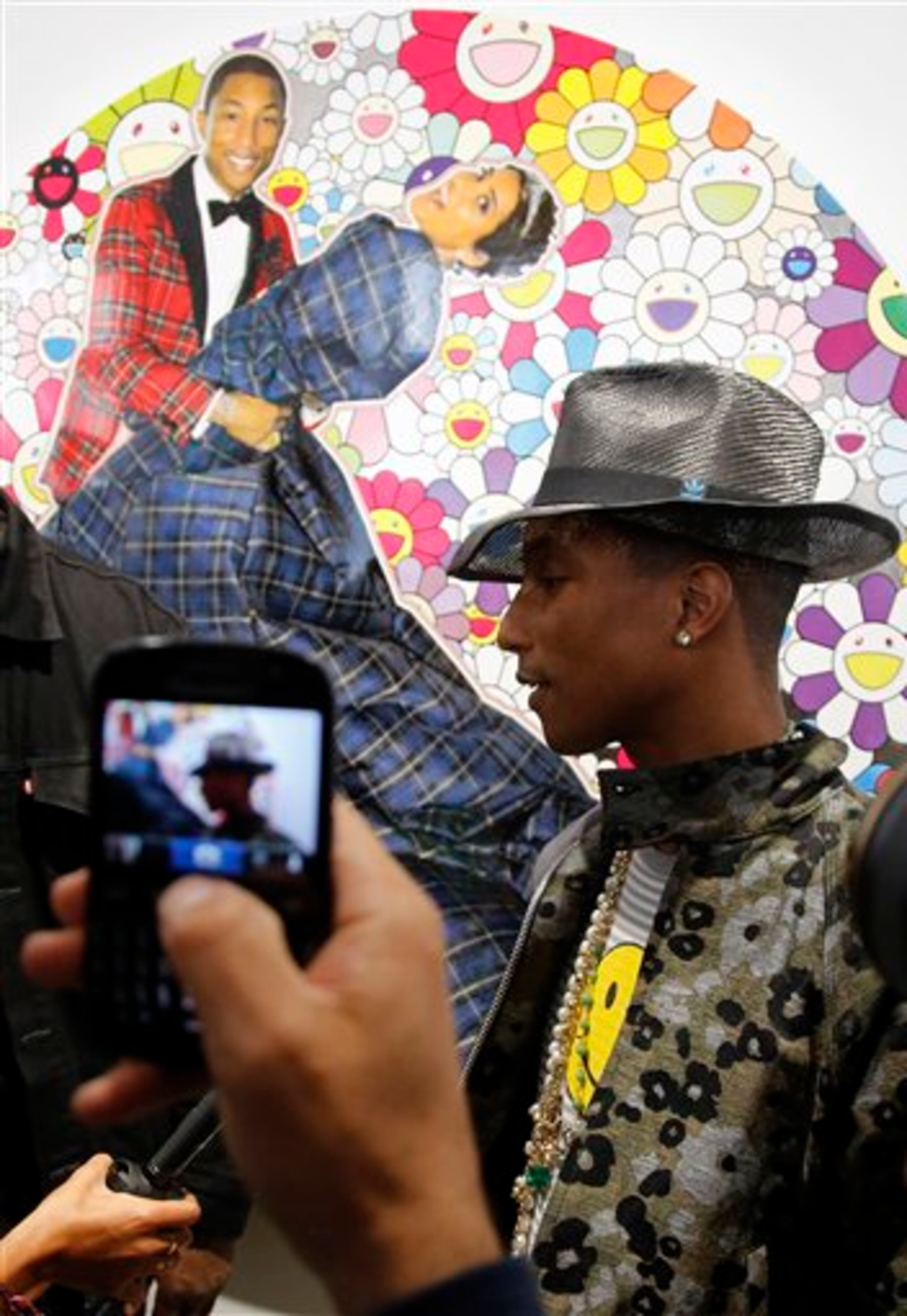 US singer Pharrell Williams poses during a press conference for the exhibition "GIRL" at the Perrotin Gallery in Paris, Monday, May 26, 2014. Williams curates an exhibition encompassing around 40 art pieces, presenting their visions of femininity, muses, female creativity and freedom. The show opens on May 27 and runs through June 27, 2014. The piece behind Williams is "Portrait of Pharrell and Helen" by Japanese artist Takashi Murakami. (AP Photo/Francois Mori)