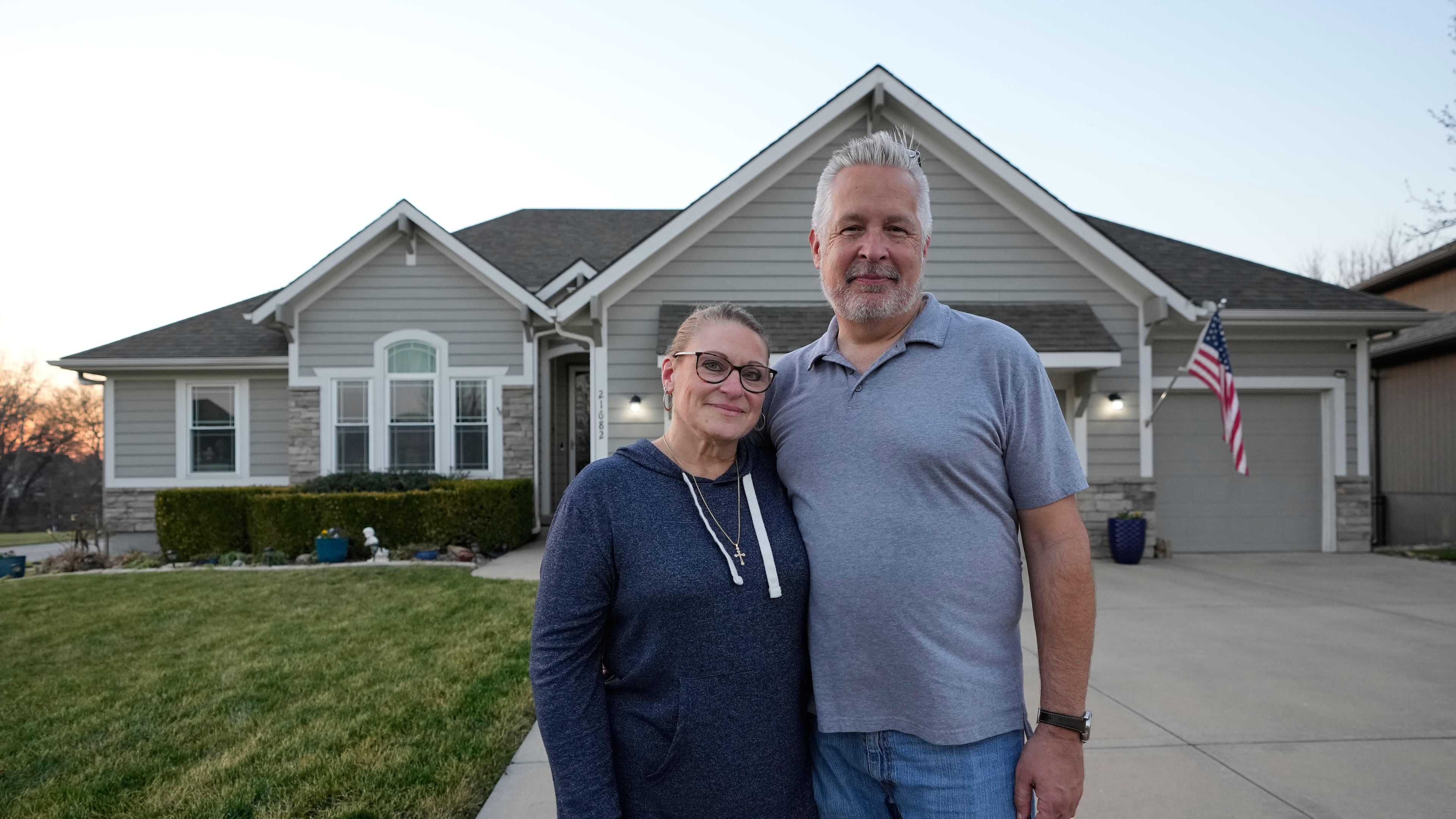 Gail and David Sanders stand in front of their home which they have been trying to sell Wednesday, March 25, 2026, in Olathe, Kan. (AP Photo/Charlie Riedel)
