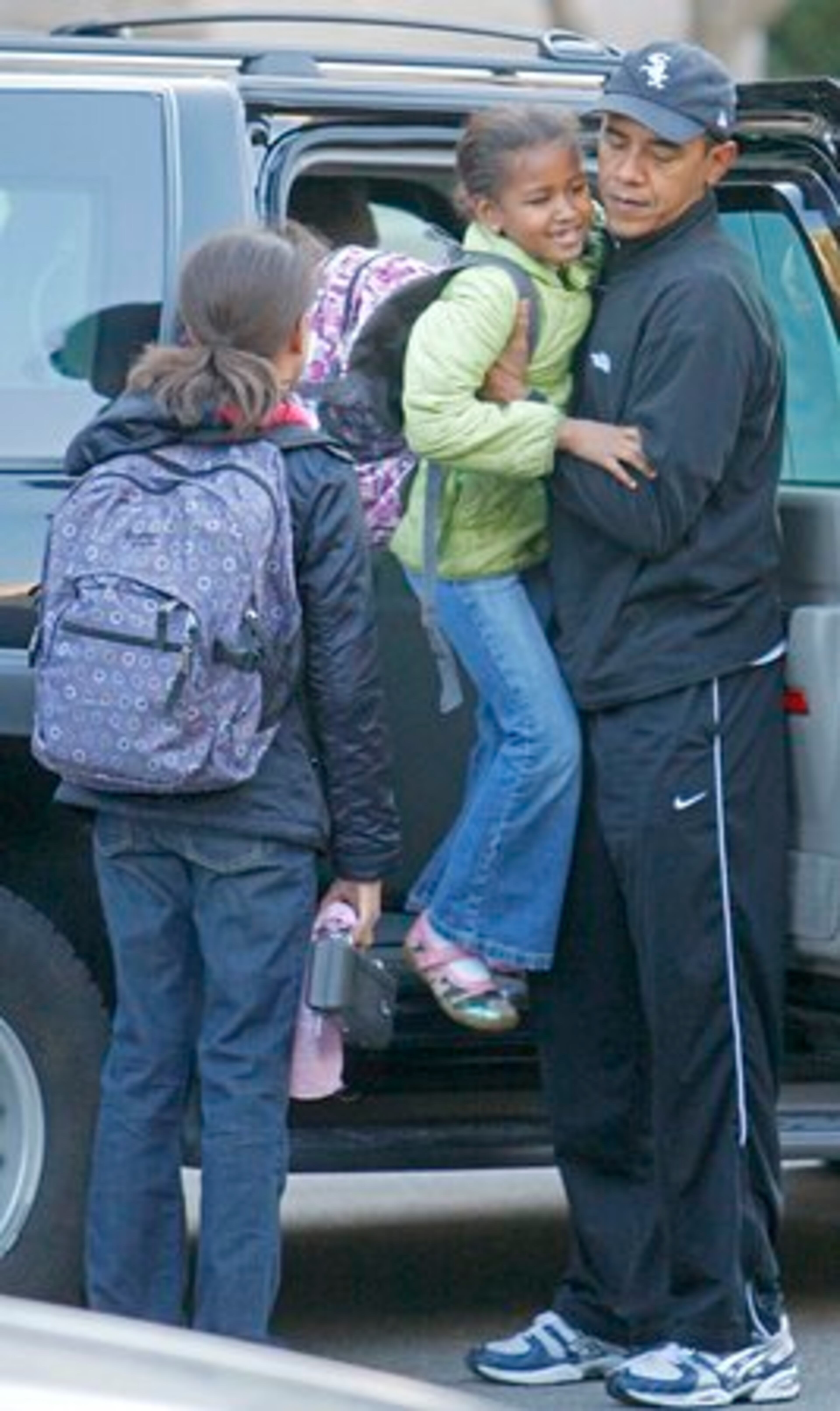 President-elect Obama lifts his daughter Sasha out of his vehicle as he drops her and her sister Malia off at school.
